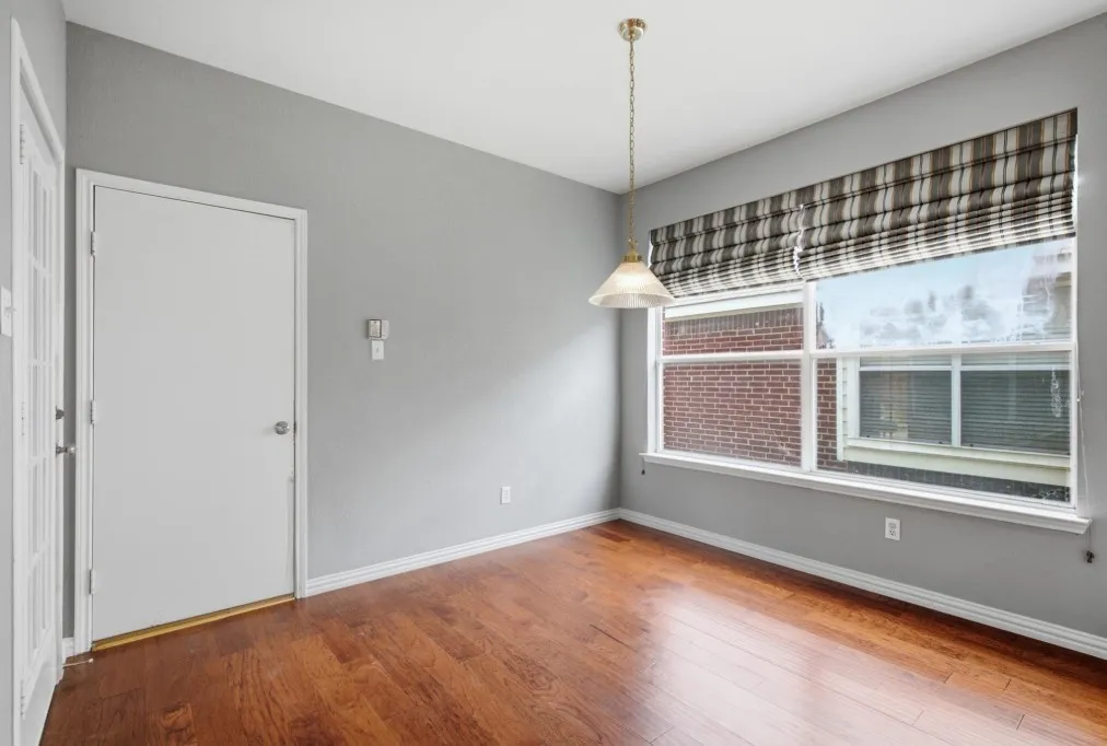 Hardwood flooring, neutral wall tones, pendant light fixture, and window with blinds