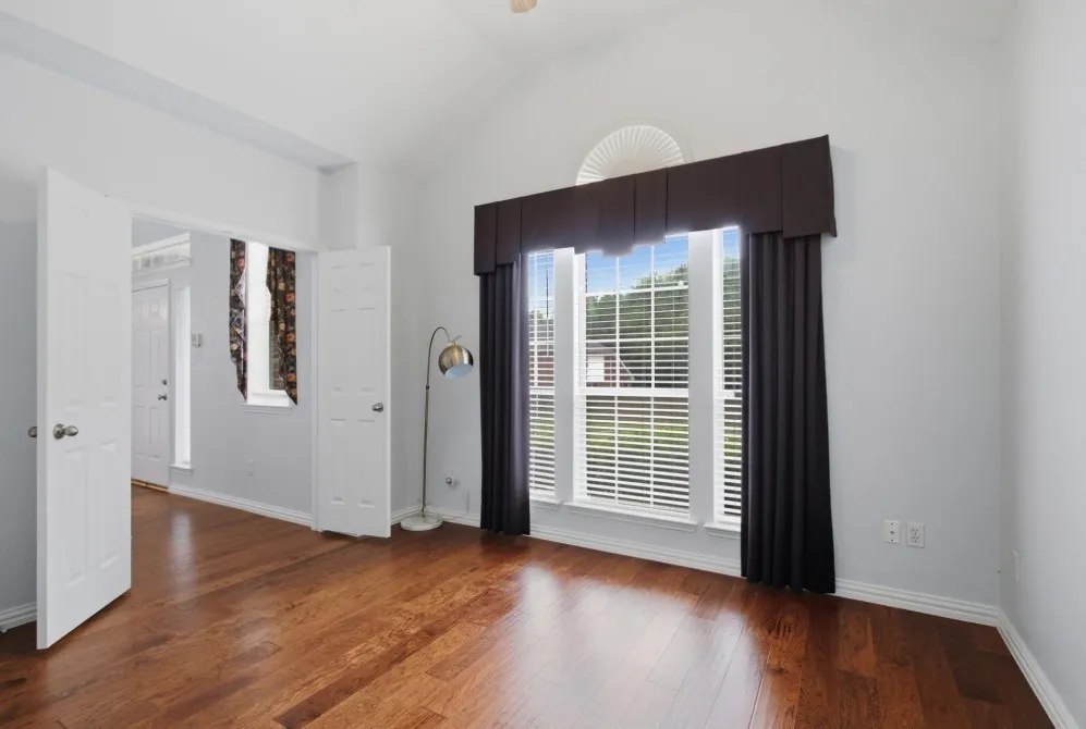 Vaulted ceiling, wood-finish flooring, broad window with louvered blinds, arched transom window, and double entry doors