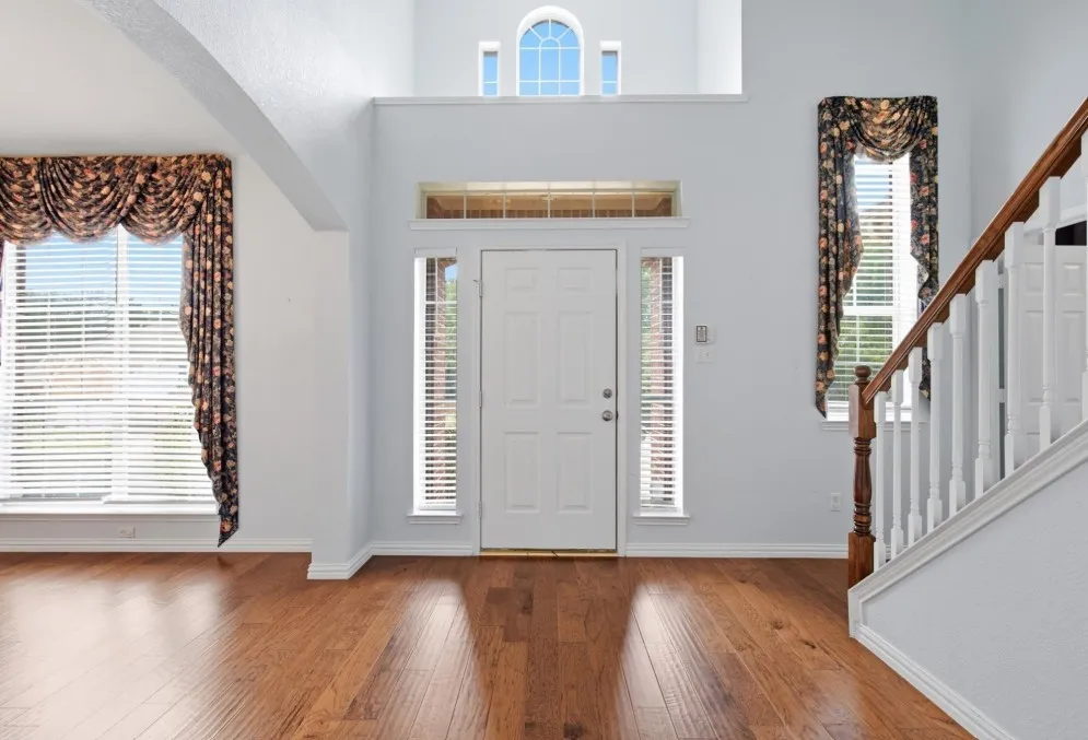 Two-story entry with wood-finish flooring, a prominent staircase, and an arched window
