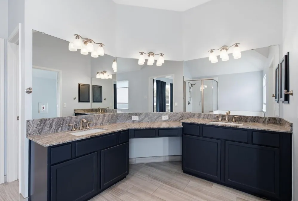 Dual vanities with stone countertops, undermount sinks, and dark cabinetry