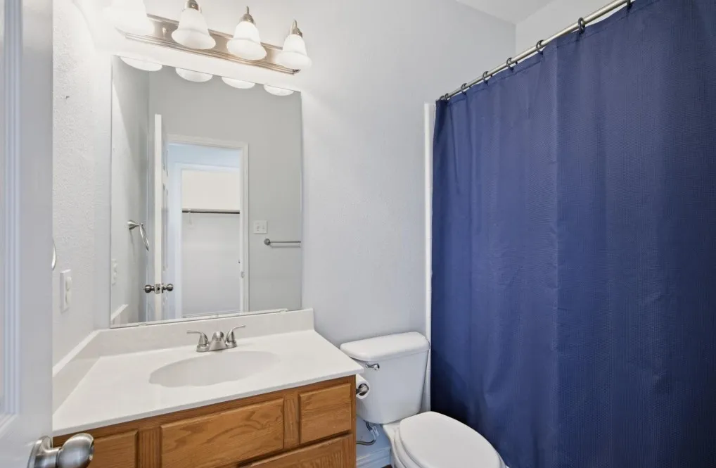 White vanity with integrated sink, wood-finish cabinetry, and brushed nickel fixtures