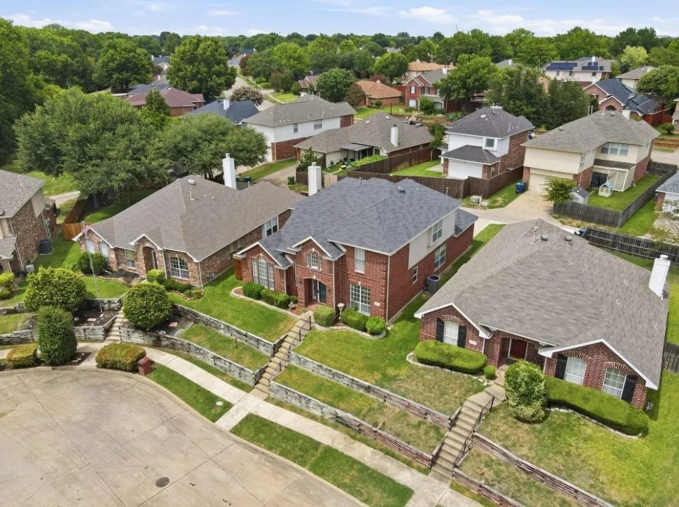 Brick exterior residence featuring a gabled roof, mature landscaping, and an integrated driveway