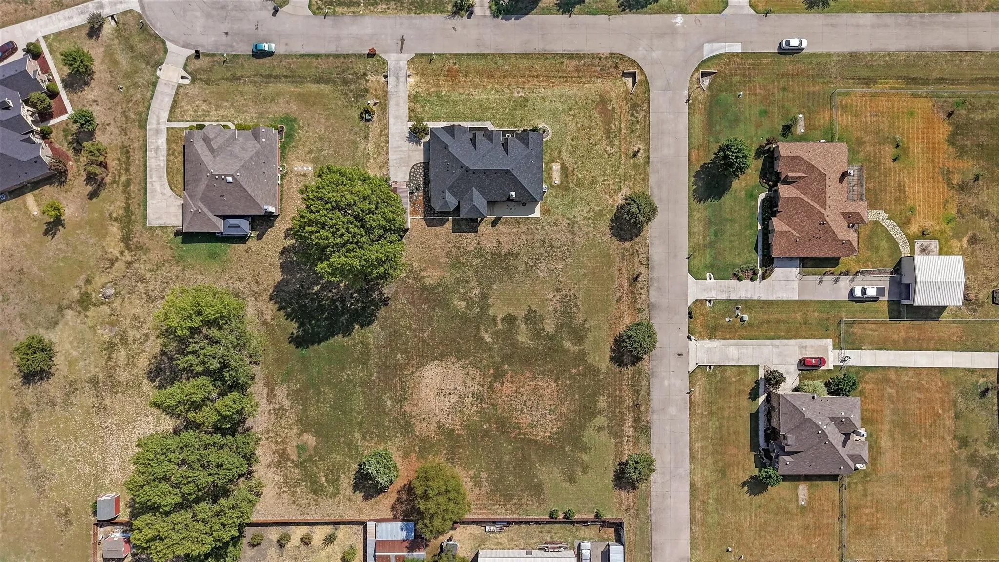 Residential property featuring a paved street, mature trees, and an expansive lot
