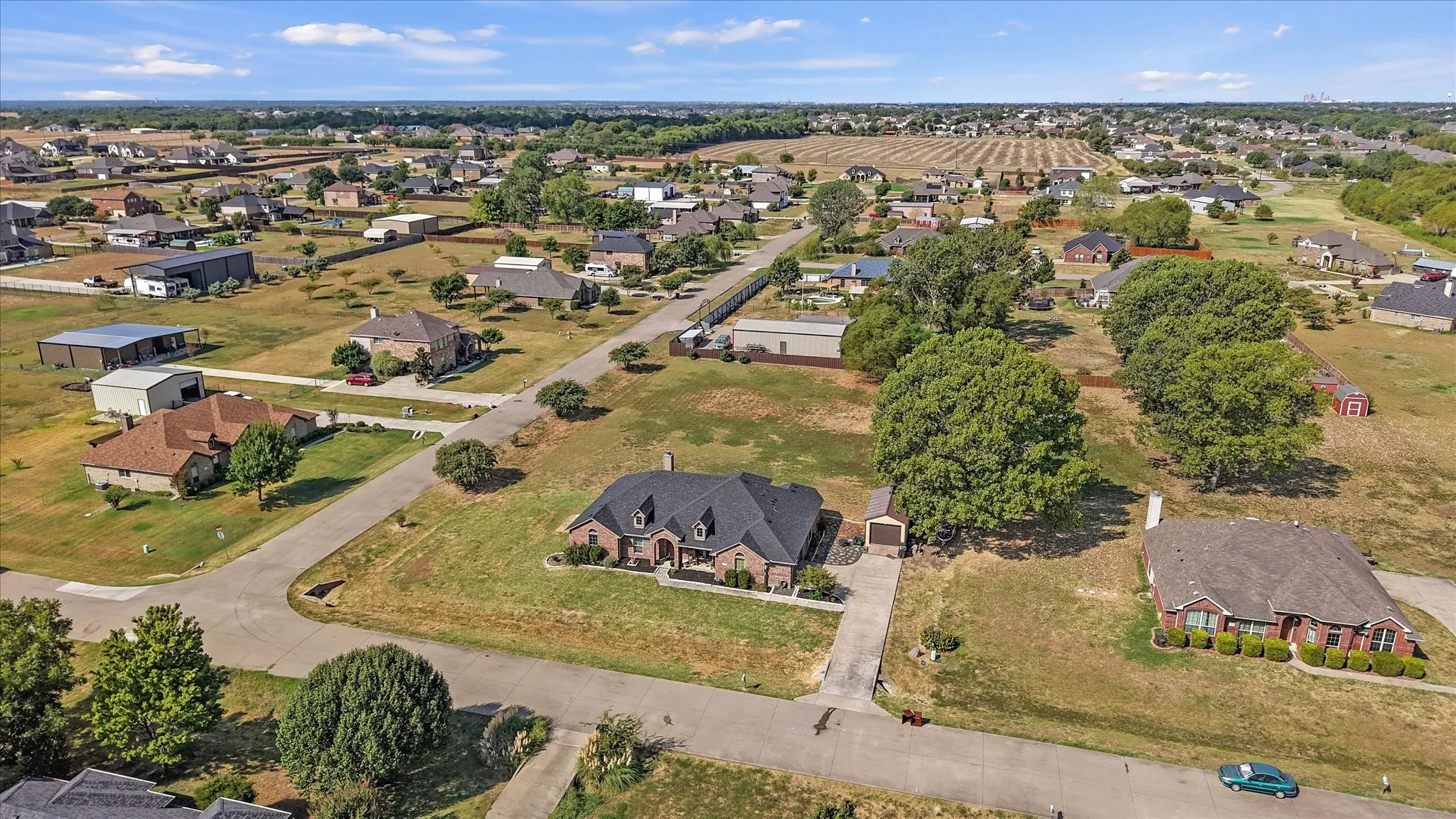 Expansive lot featuring a brick residence, a long paved driveway, and mature trees