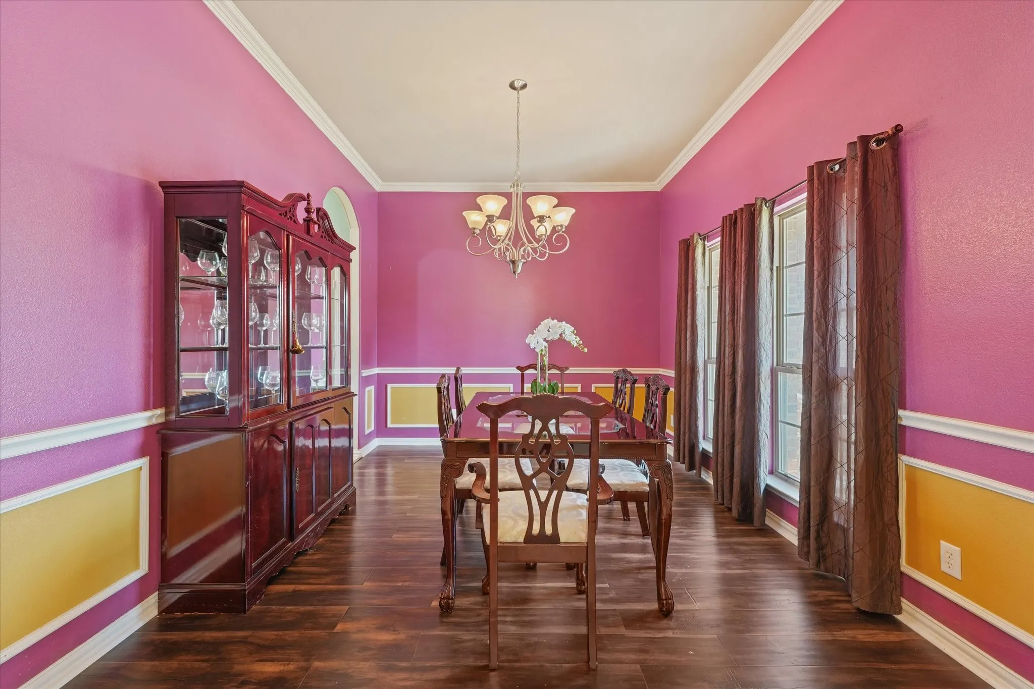 Wood-finish flooring, crown molding, chair rail molding, and multiple windows with transoms