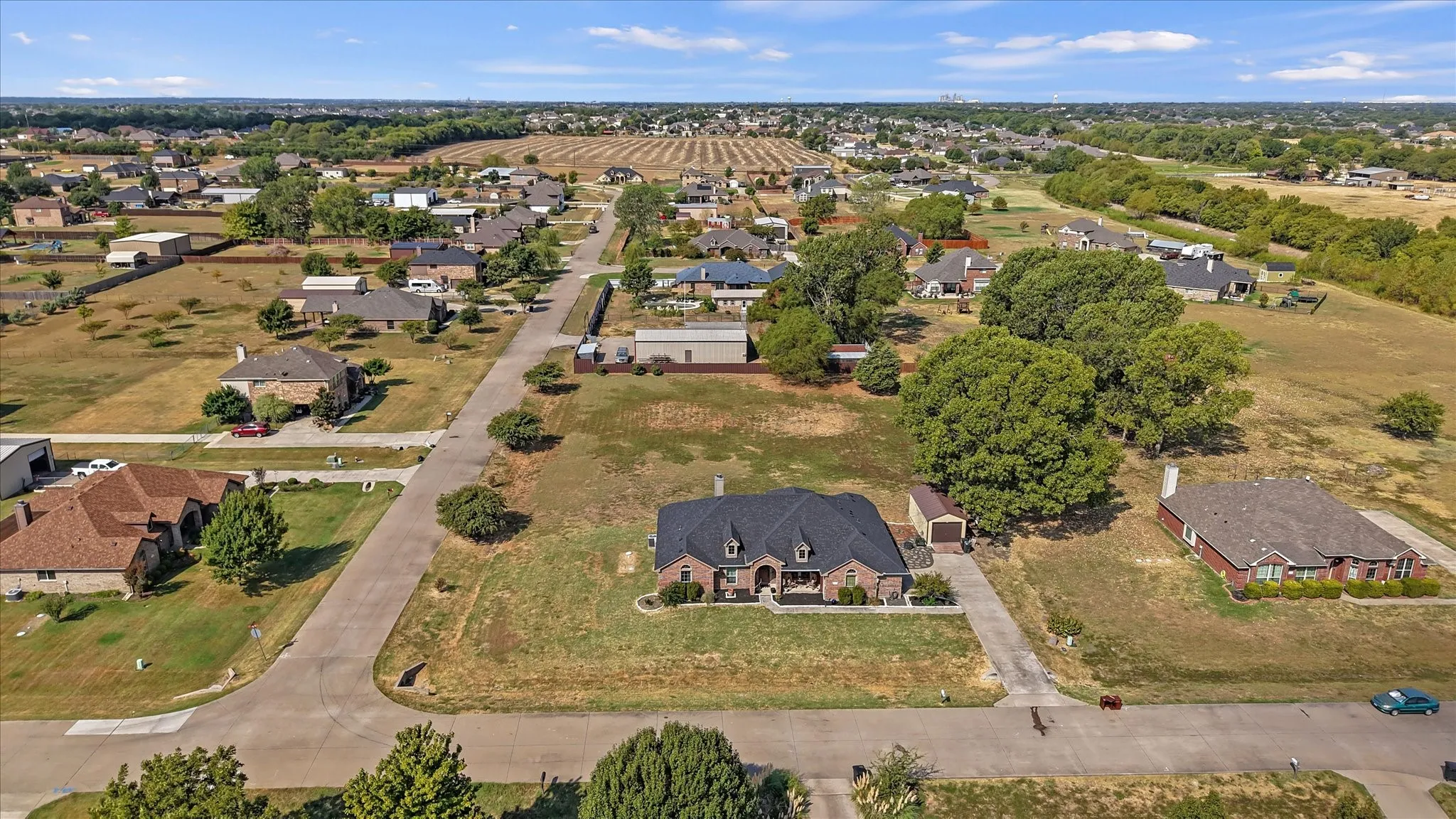 Brick exterior residence with a dark shingle roof, attached garage, and a long concrete driveway