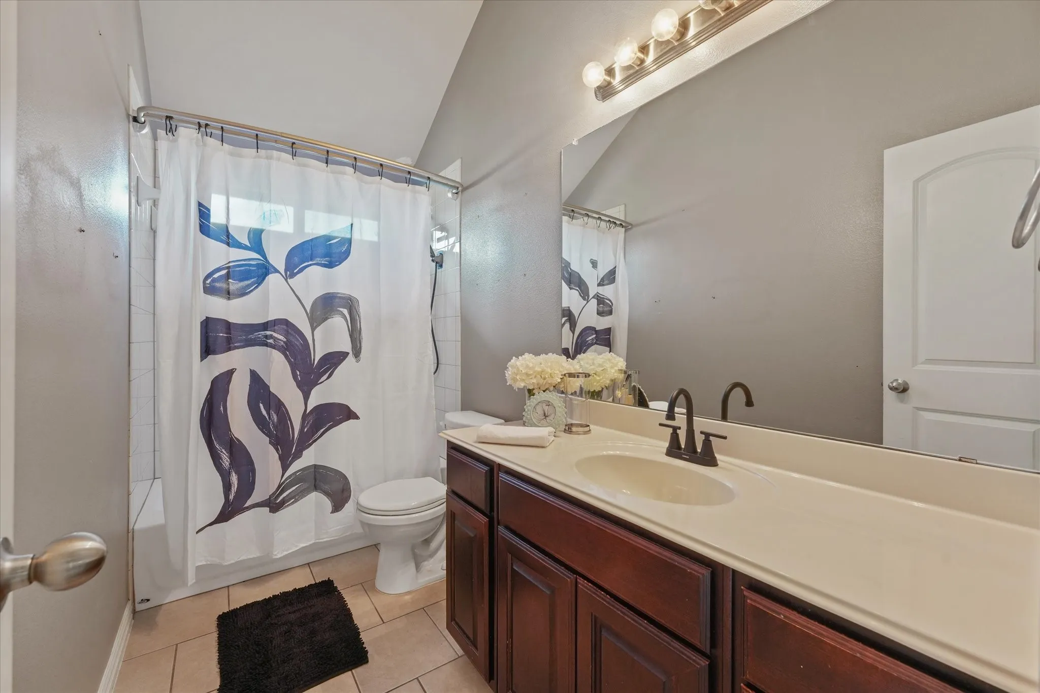 Bathroom featuring a single vanity with a dark wood-finish cabinet, integrated countertop and sink, and a black-finish faucet