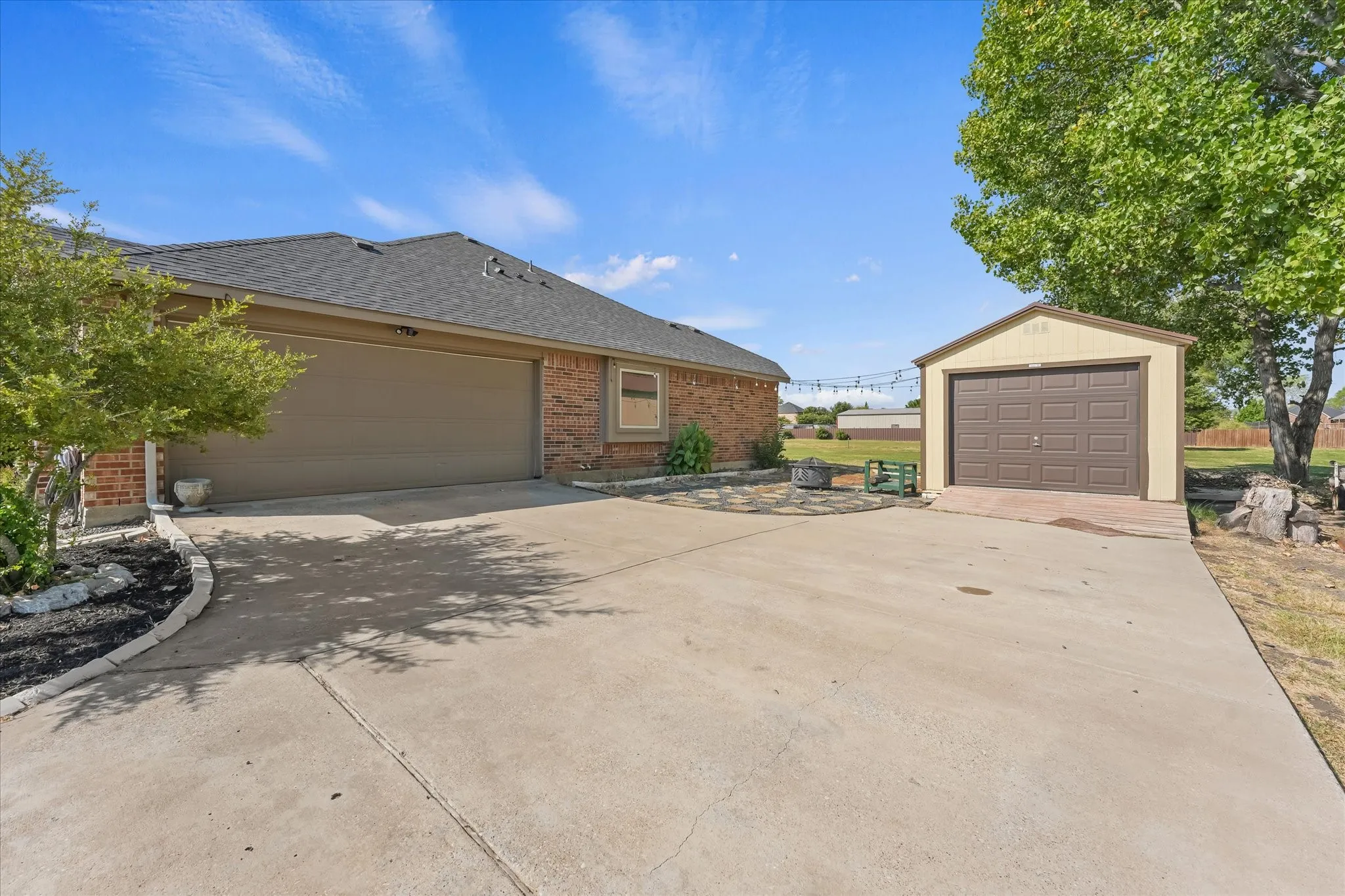 Brick-clad exterior with a two-car garage, concrete driveway, and a detached storage shed