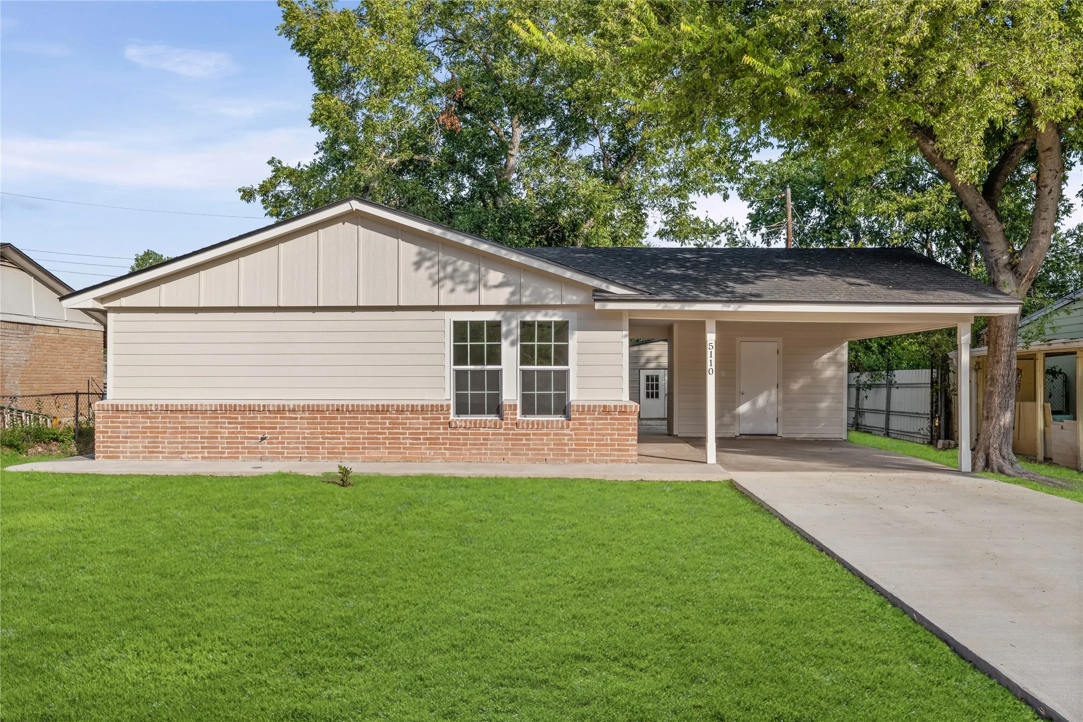 Single-story residence featuring a carport, brick wainscoting, and a gabled roofline