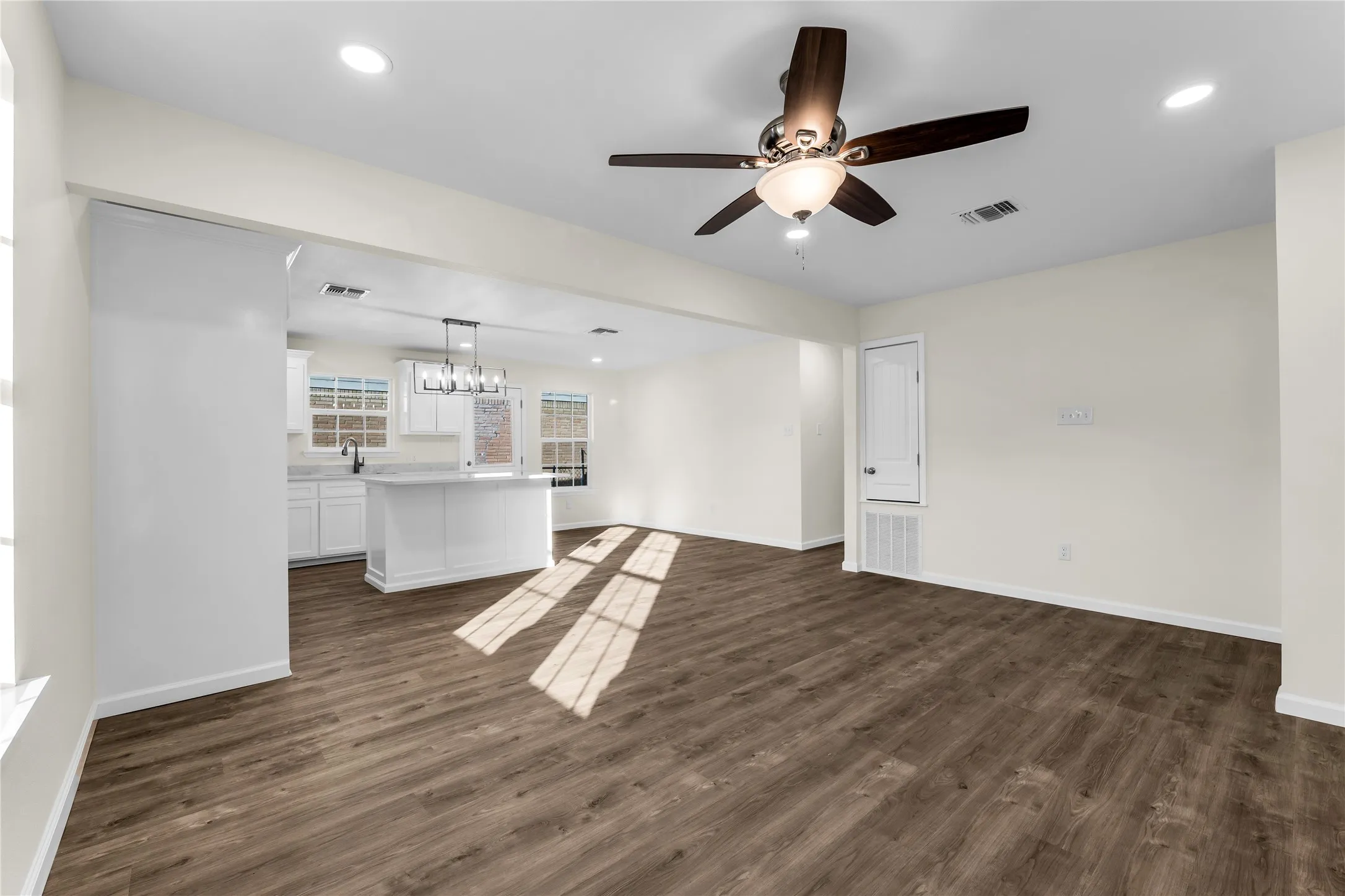 Expansive wood-finish flooring, recessed lighting, and a modern ceiling fan