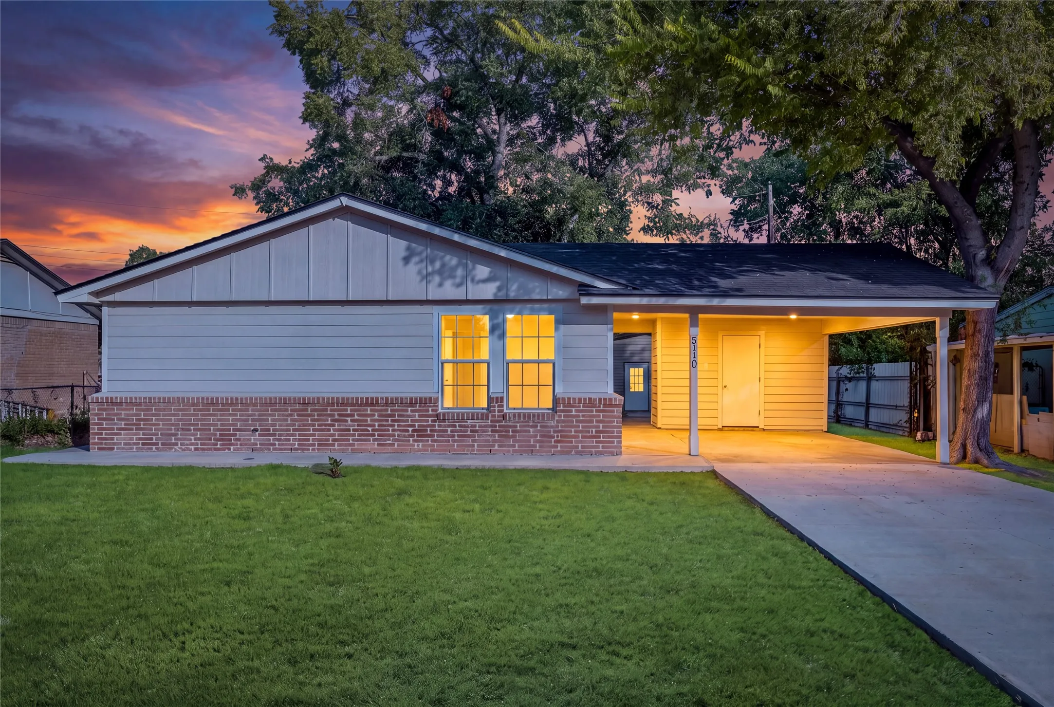 Brick and siding exterior with a covered carport, concrete driveway, and established lawn