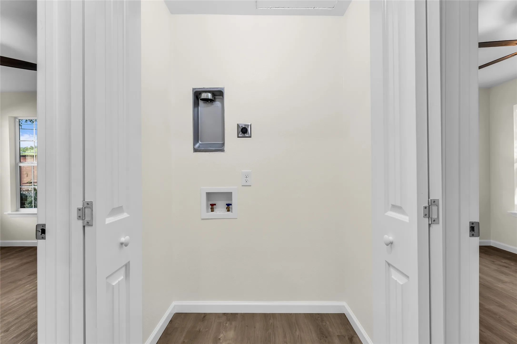 Dedicated laundry alcove with utility hookups and wood-finish flooring