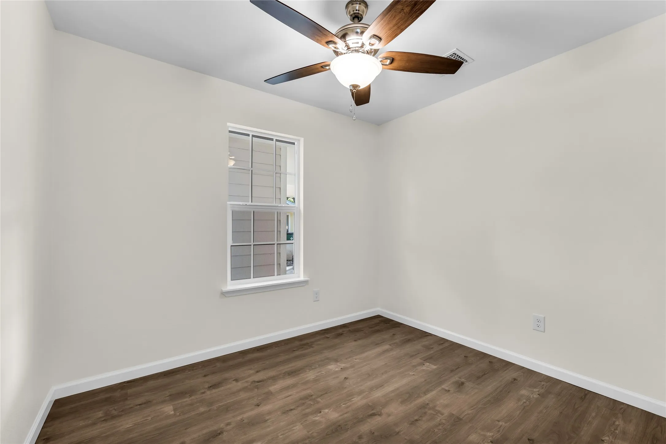Wood-finish flooring, white trim, single window, and a ceiling fan with integrated lighting