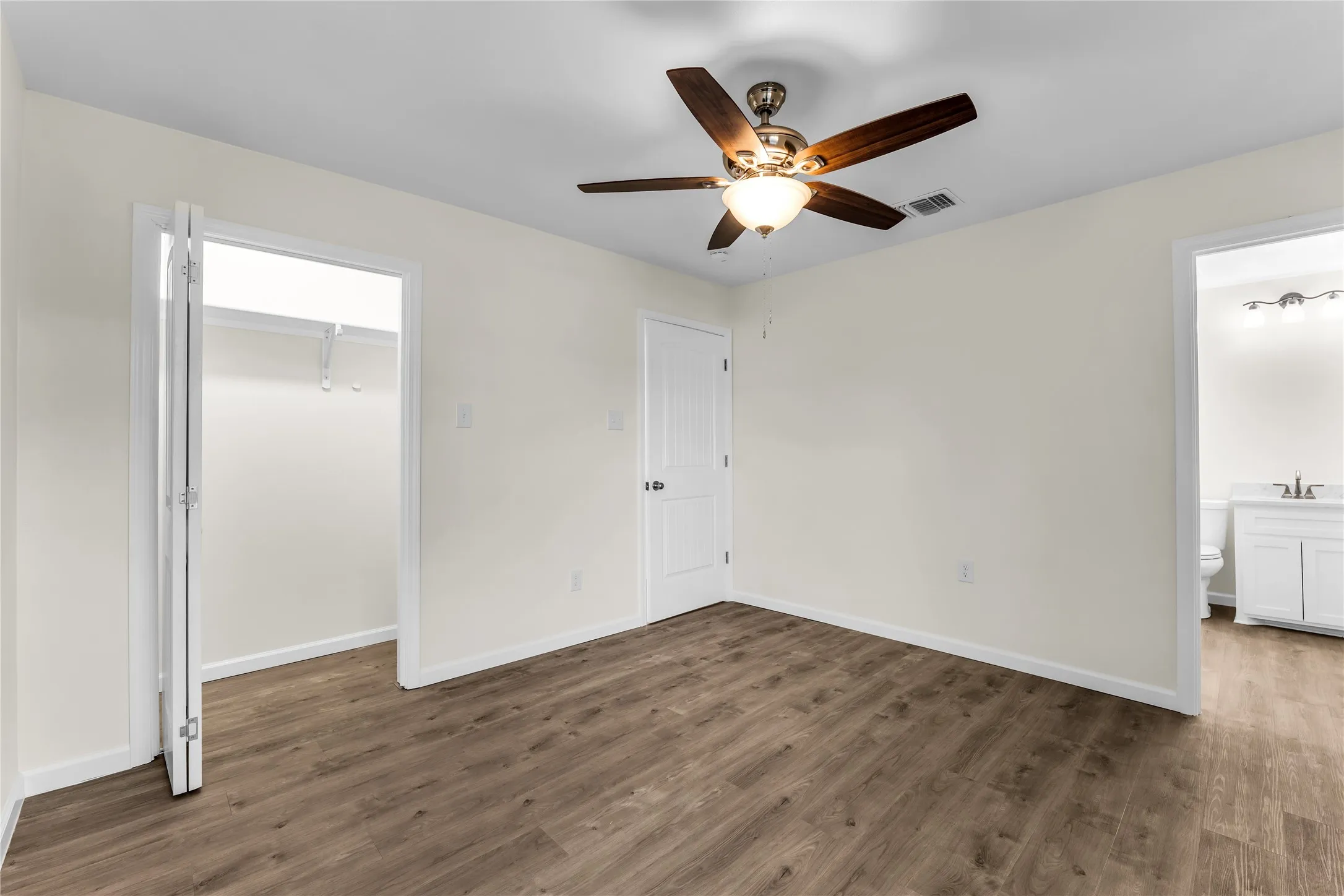 Wood-finish flooring, ceiling fan with integrated lighting, and a closet with bi-fold doors
