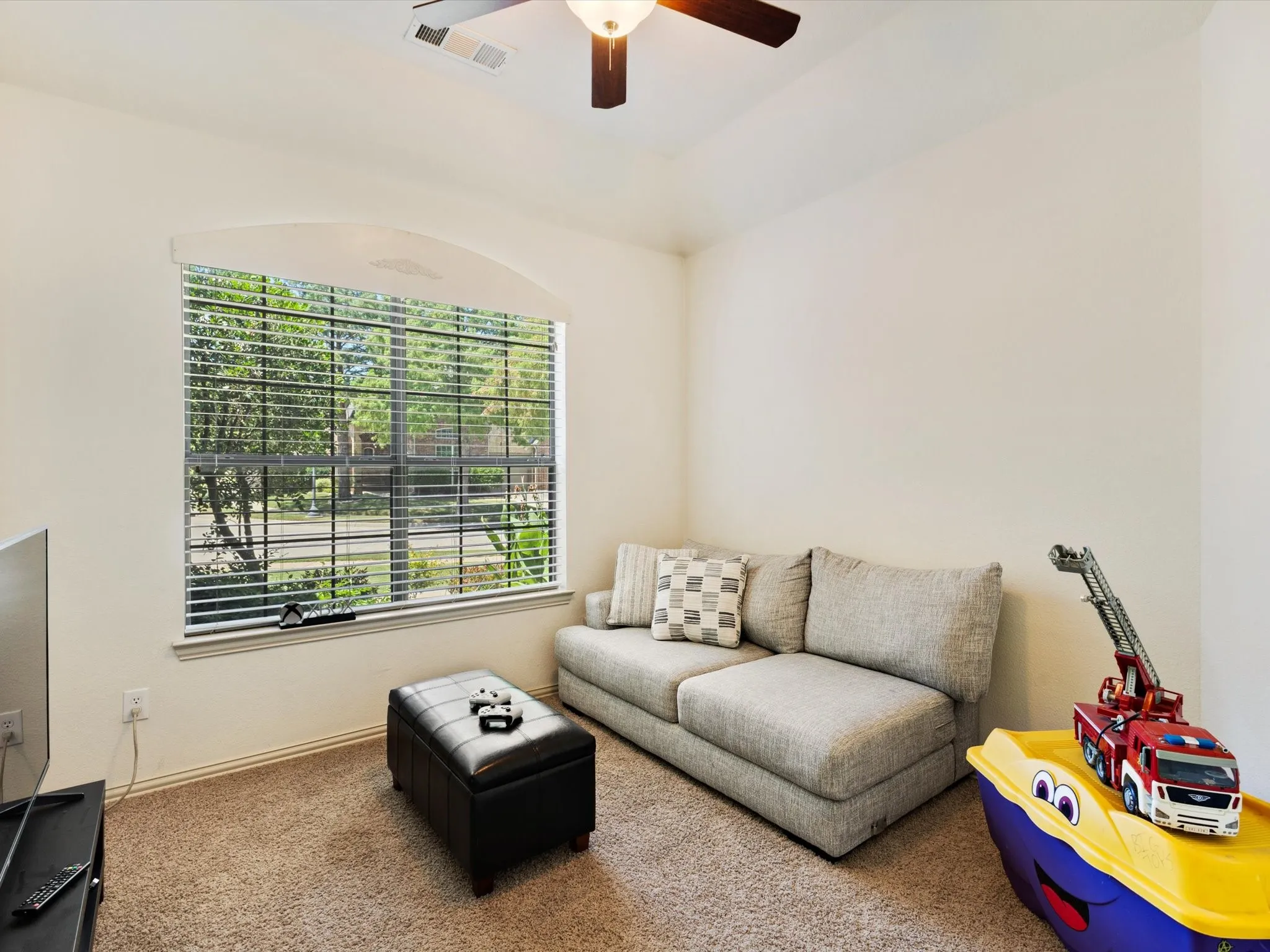 Arched window with blinds, carpeted flooring, and a ceiling fan with integrated lighting