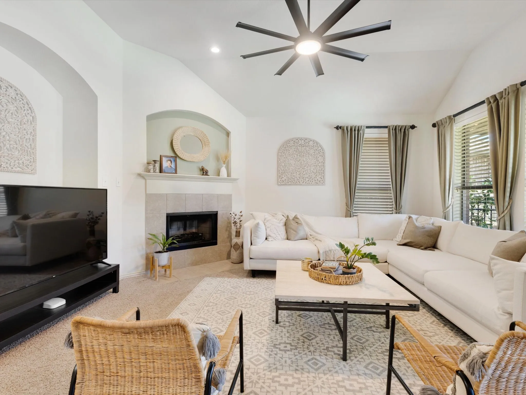 Vaulted ceilings, tile-surround fireplace, large windows with blinds, and a contemporary ceiling fan