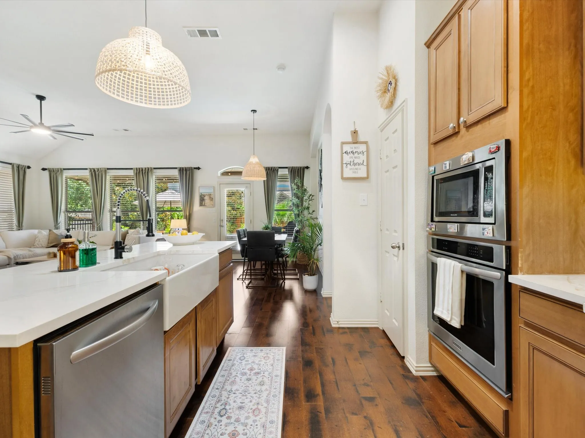 Open-concept kitchen with wood-finish flooring, a farmhouse sink, stainless steel appliances, and a central island with countertop seating