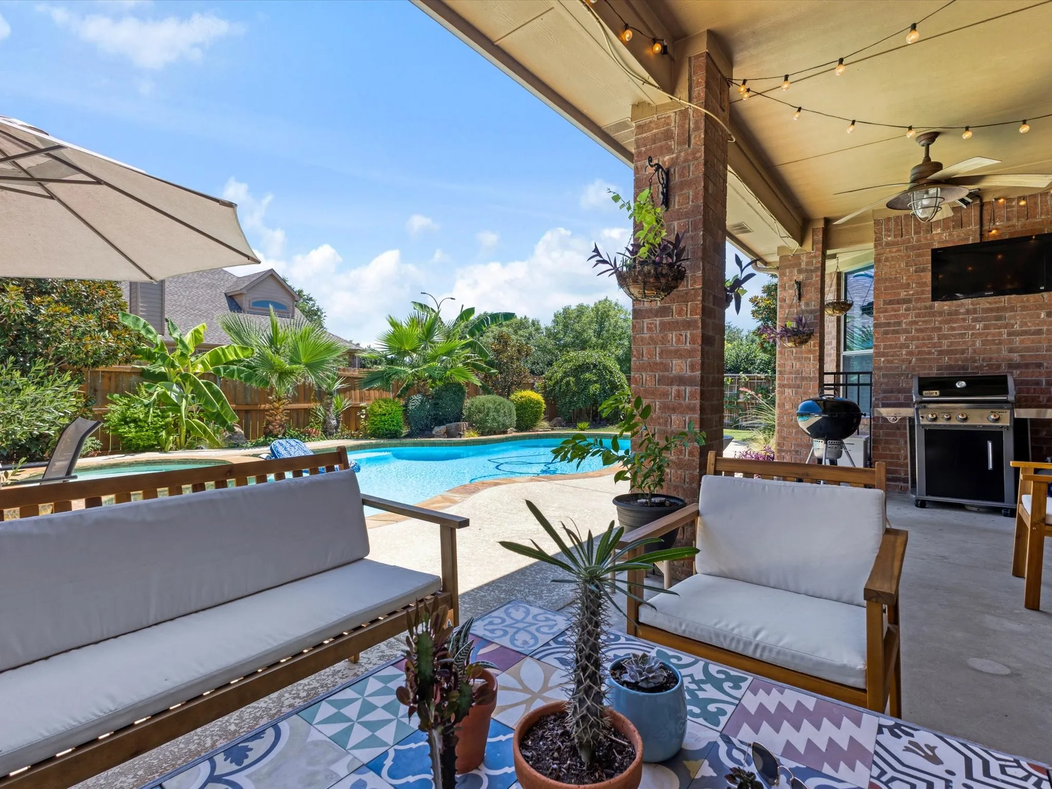 Covered patio with brick columns, ceiling fan, and built-in grill station