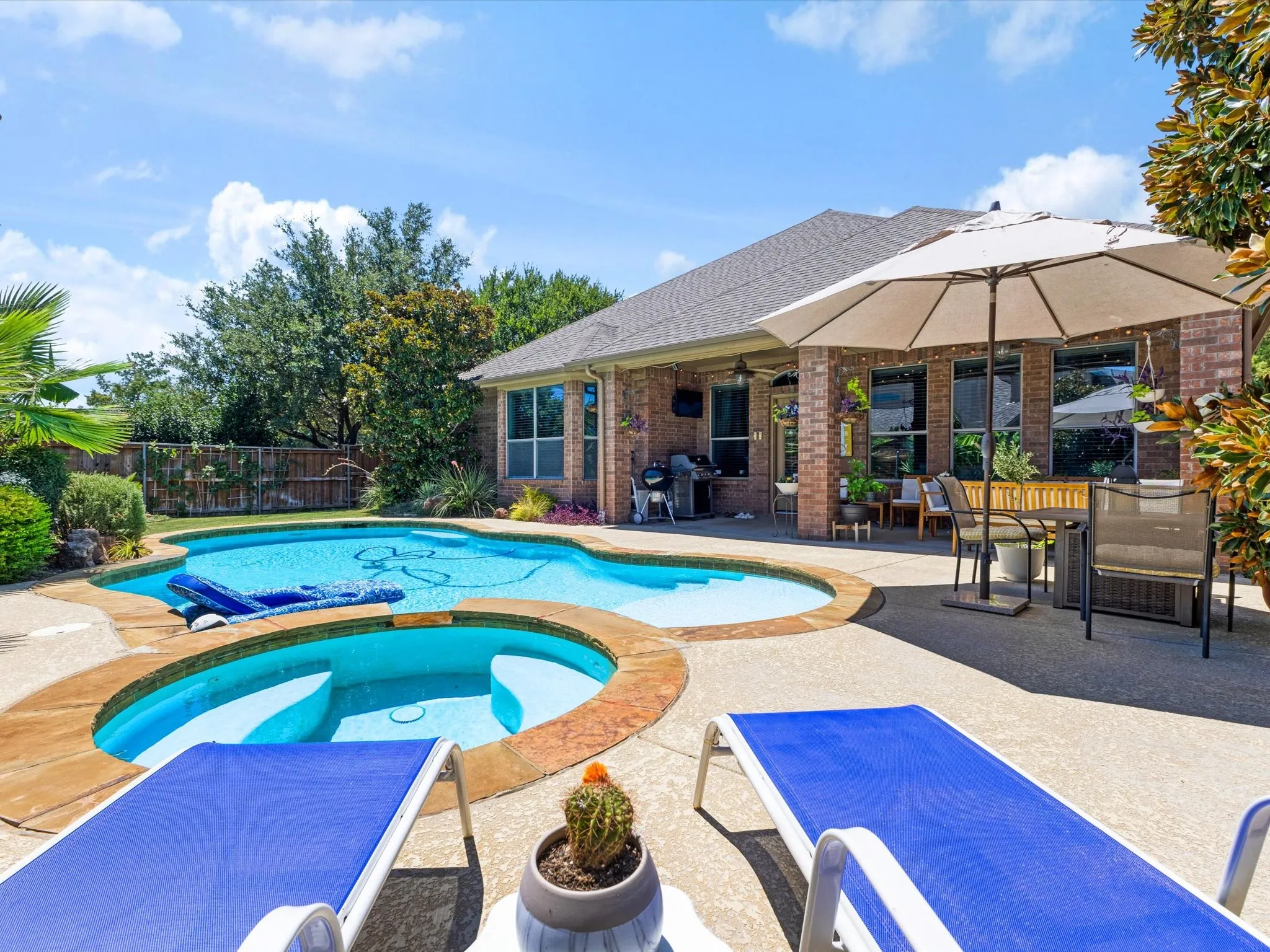 Spacious backyard featuring a freeform pool, integrated spa, and extensive concrete patio