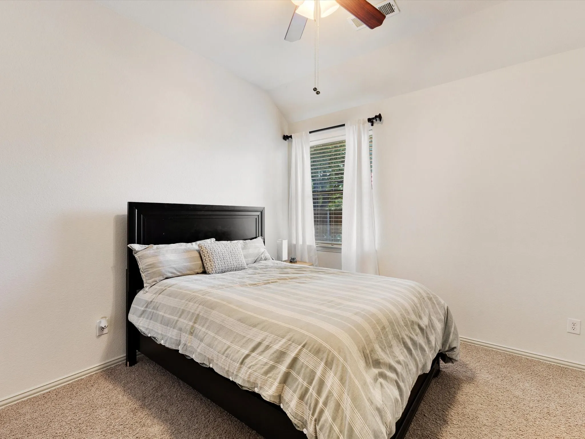 Vaulted ceiling, ceiling fan with light fixture, window with blinds, and carpeted flooring
