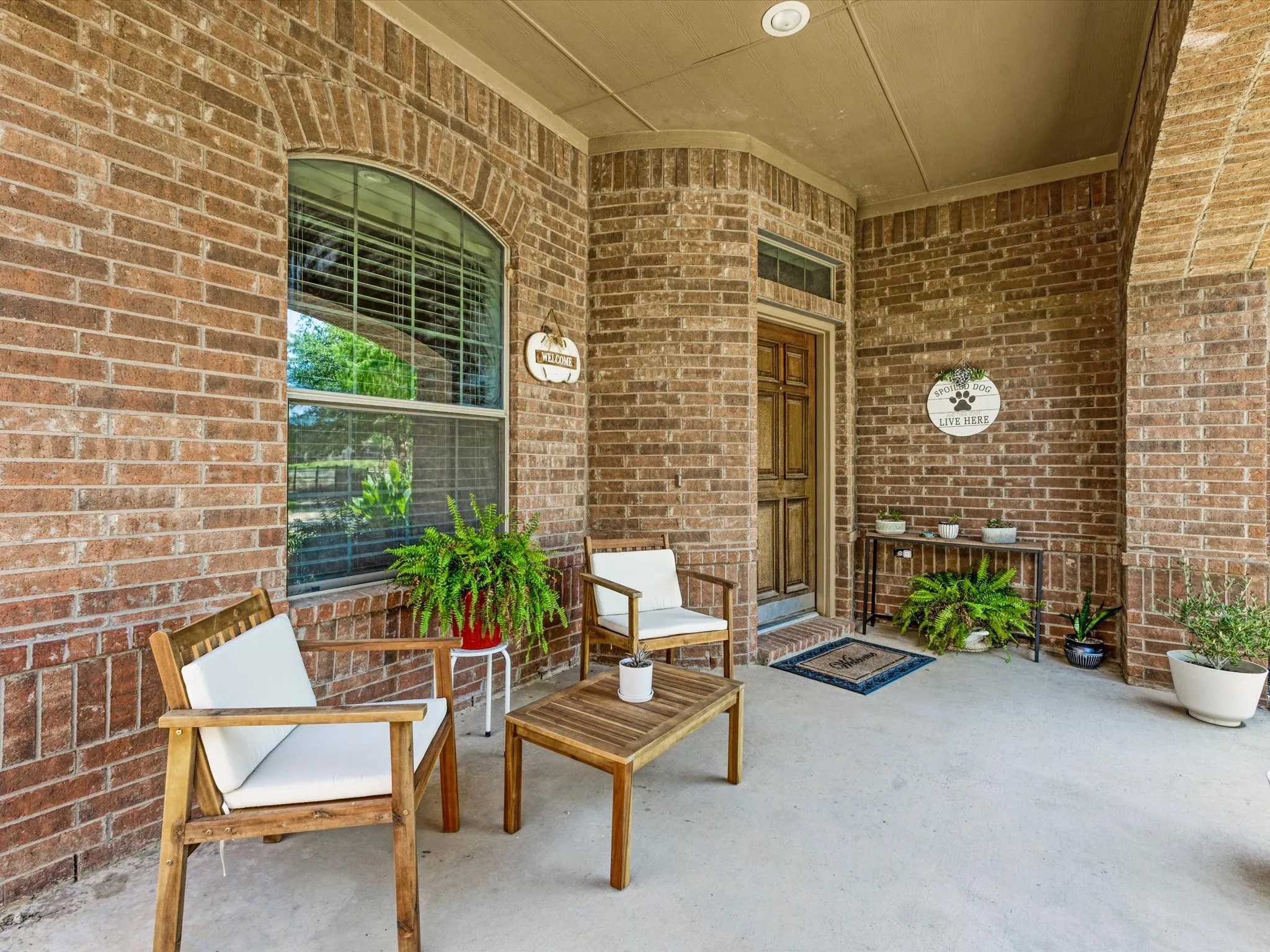 Brick exterior with an arched window, covered porch, wood-paneled entry door, and recessed lighting