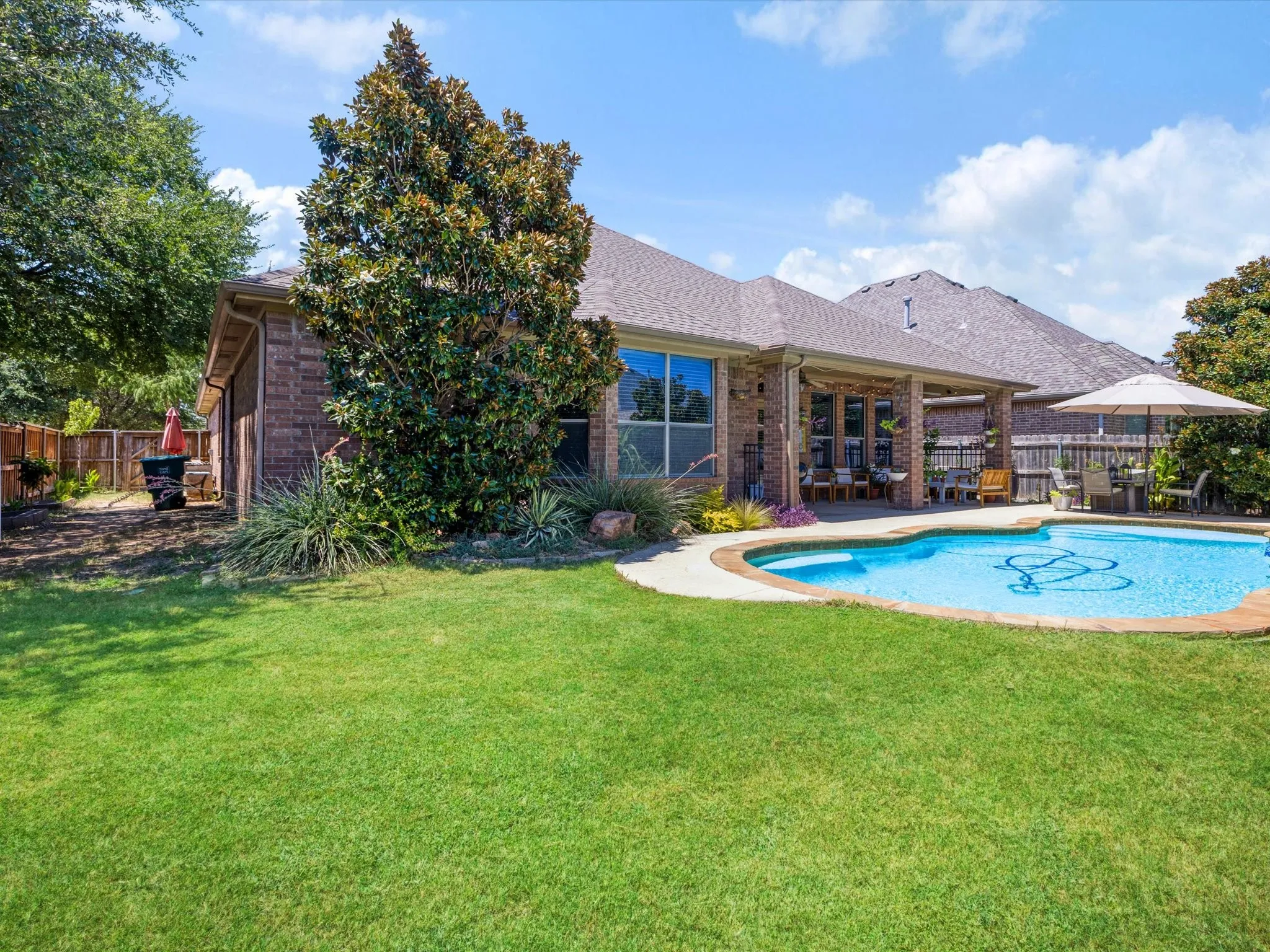 Brick exterior with covered patio, integrated pool, and fenced perimeter