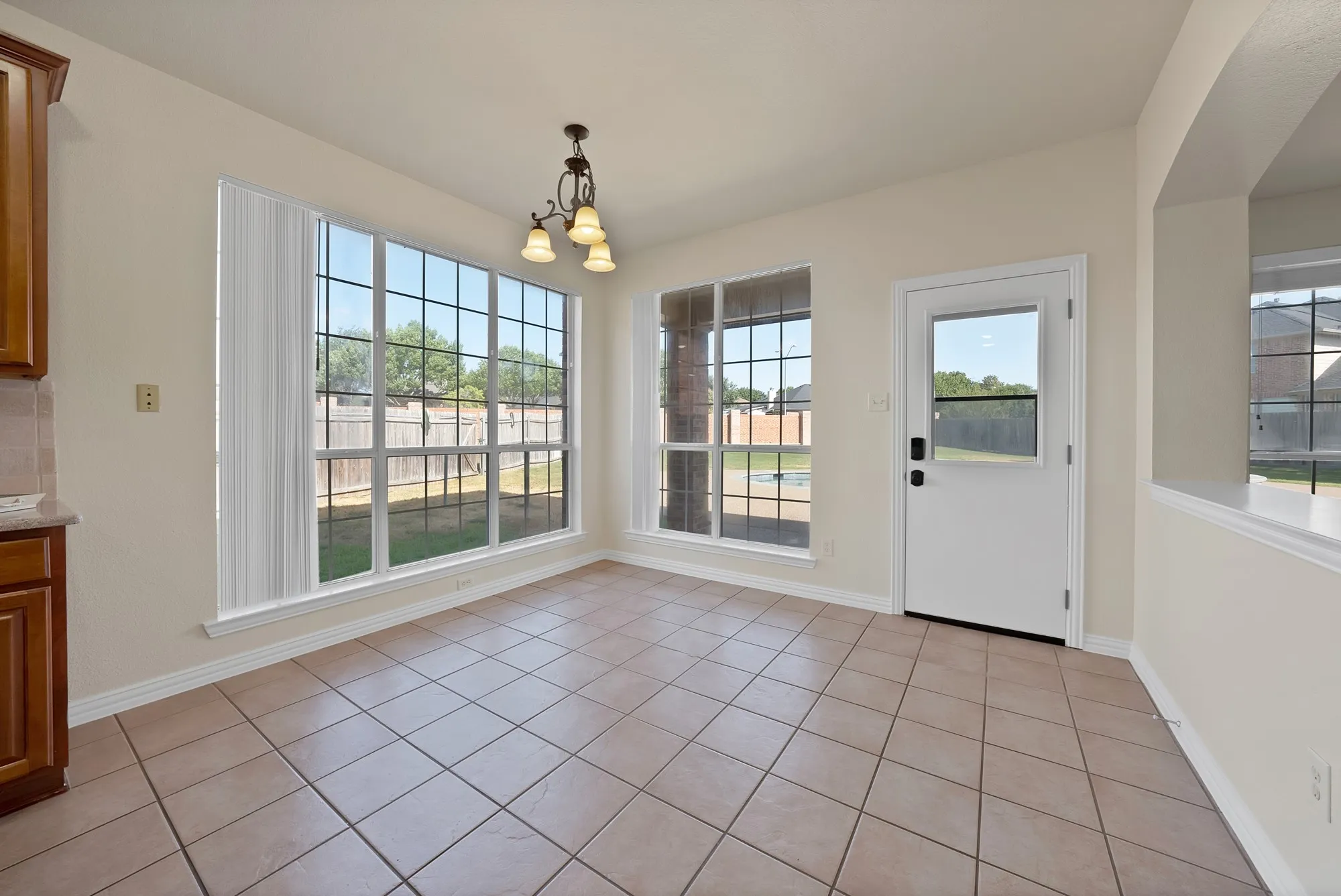 Tiled flooring with large windows, a side door with a window, and an archway
