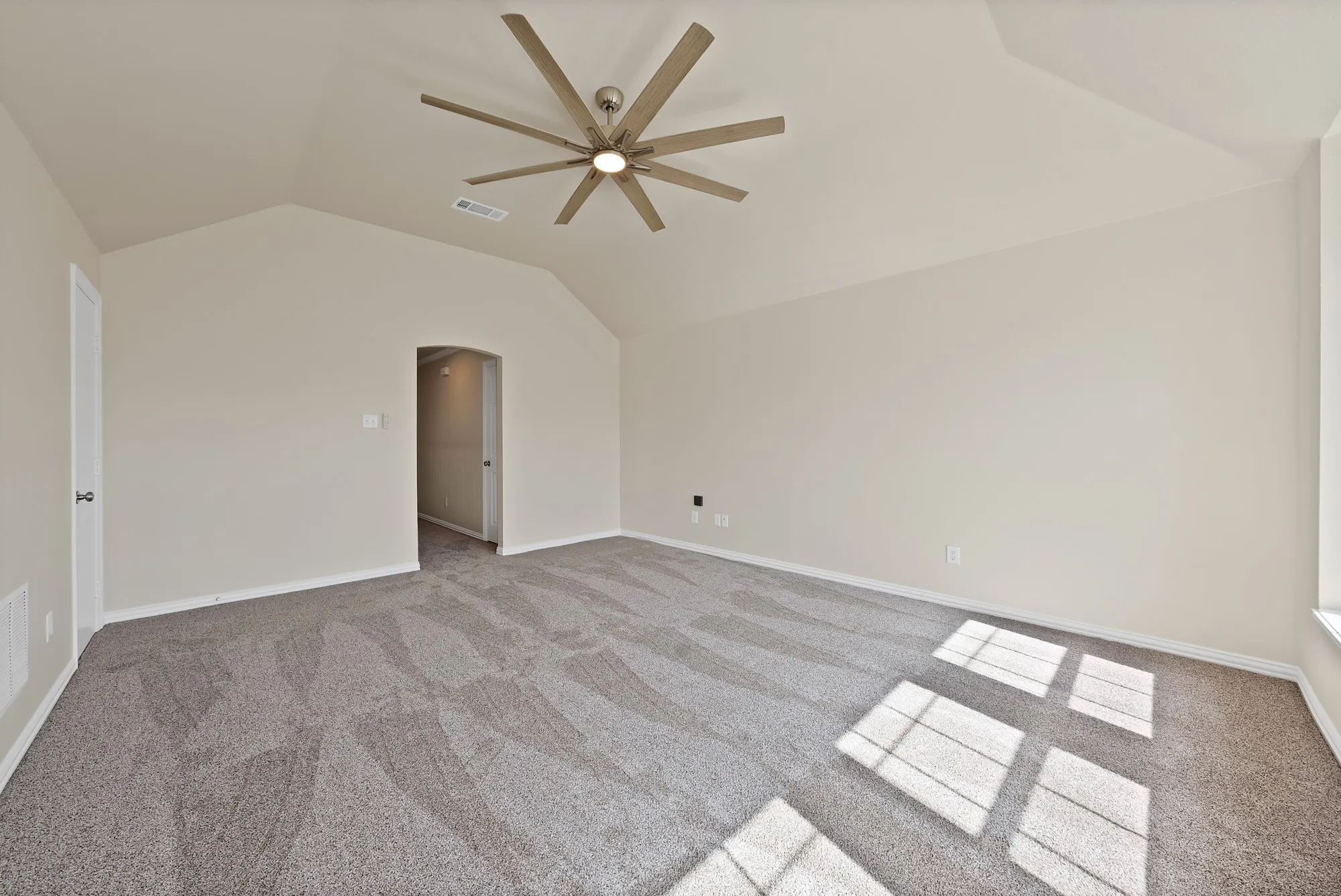 Vaulted ceiling with a contemporary ceiling fan, patterned carpet, and neutral wall tones