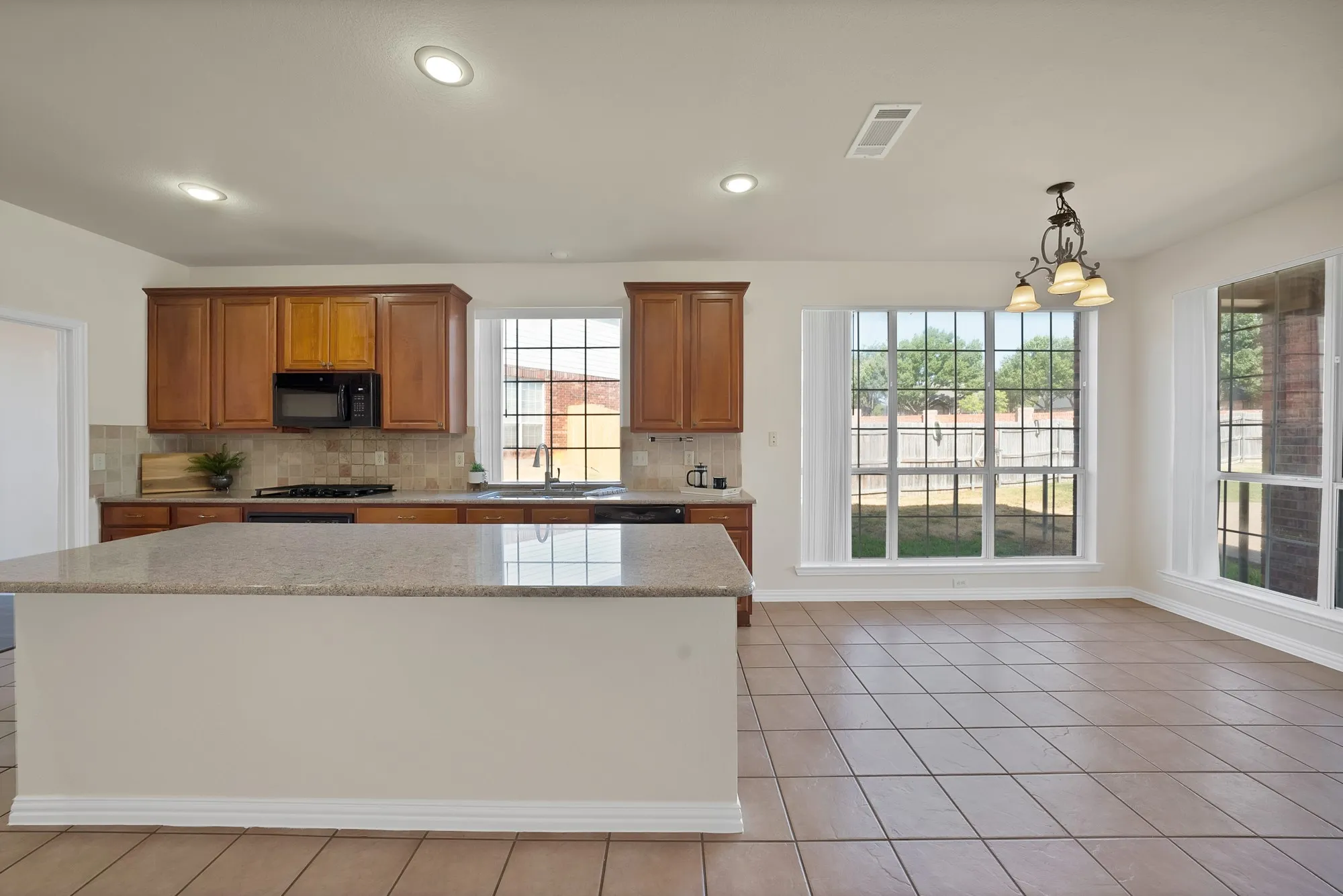 Kitchen island featuring a light-toned countertop, wood cabinetry, tile backsplash, and recessed lighting