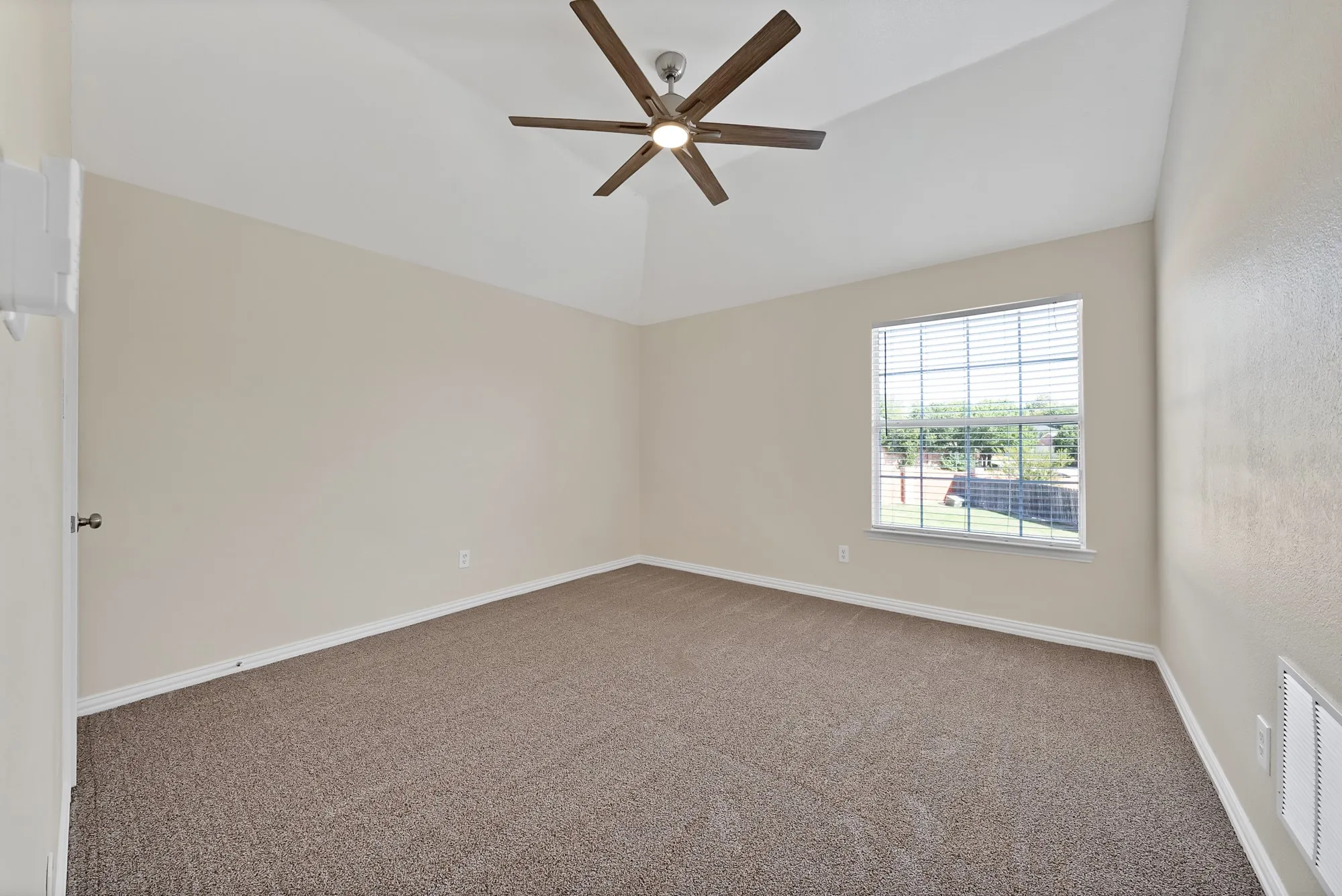 Vaulted ceiling, ceiling fan with integrated lighting, neutral wall tones, carpeted flooring, window with blinds
