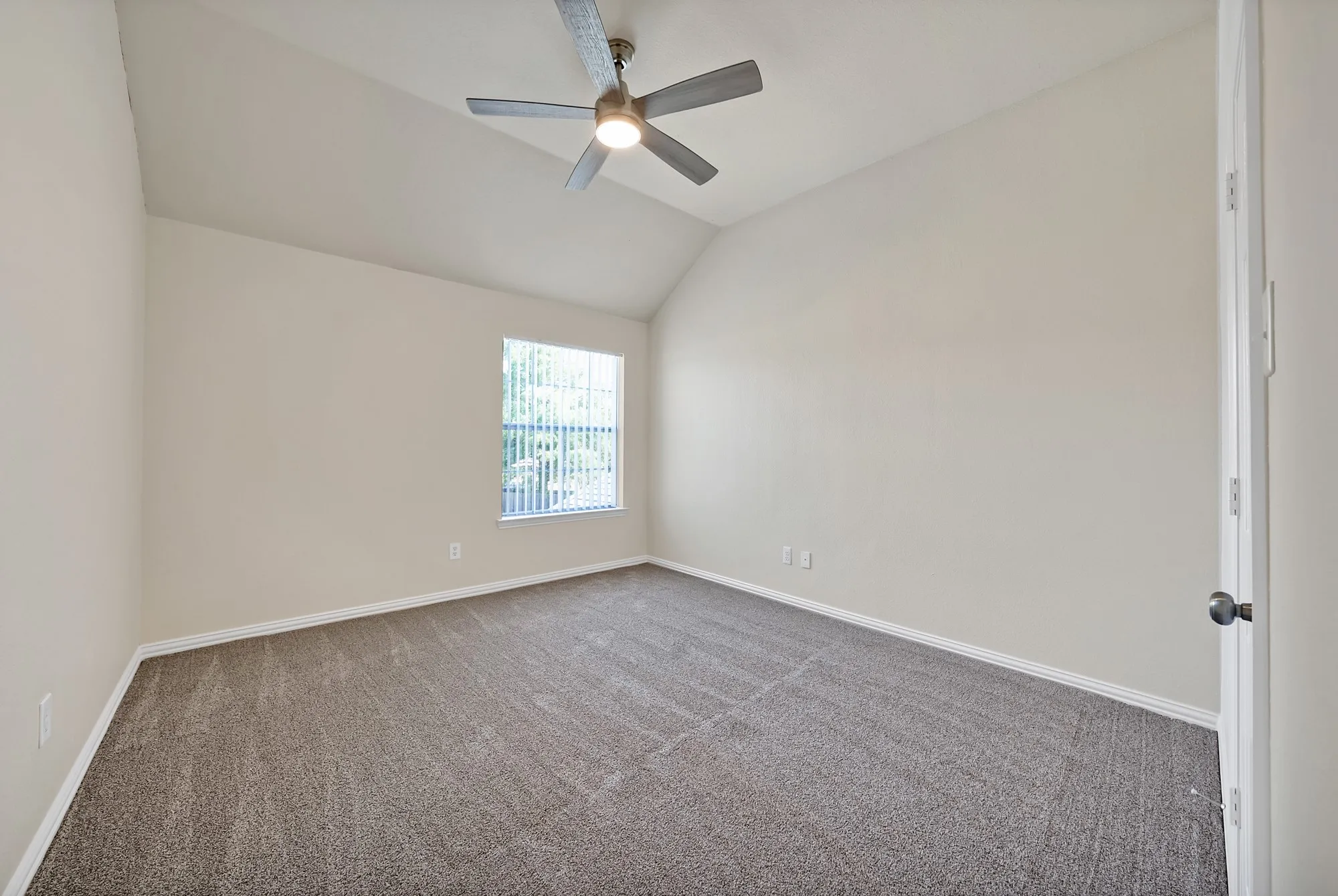 Vaulted ceiling room featuring neutral carpet, a single window with blinds, and a ceiling fan with integrated lighting