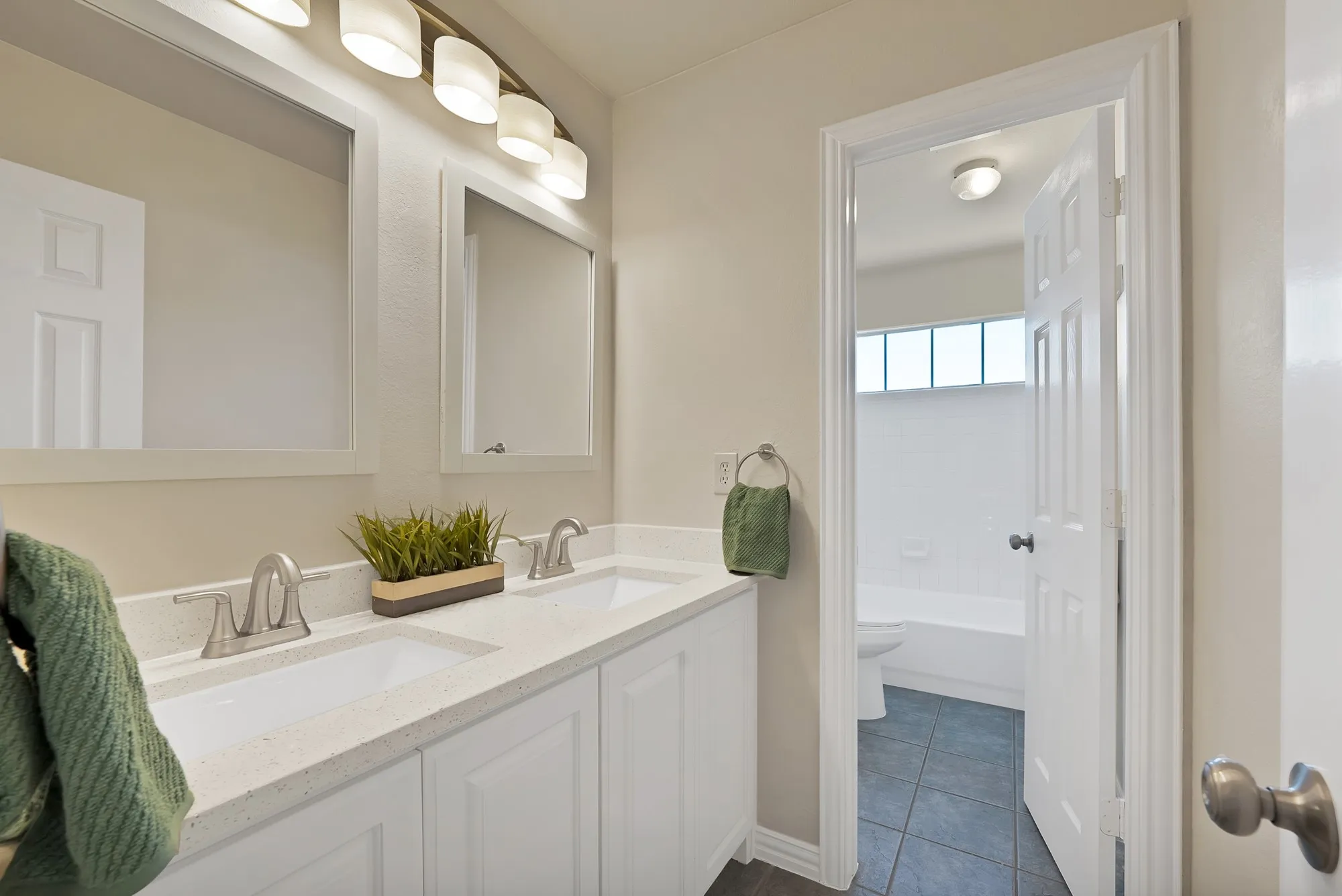 Dual vanity with white cabinetry, light-toned countertop, and brushed nickel fixtures
