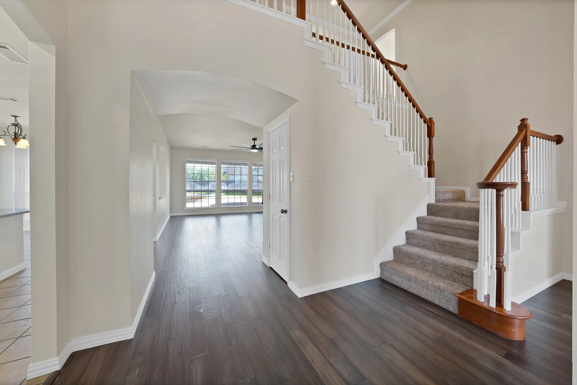 Two-story staircase with wood-finish handrails and carpeted treads, wood-finish flooring, vaulted ceilings, and large windows