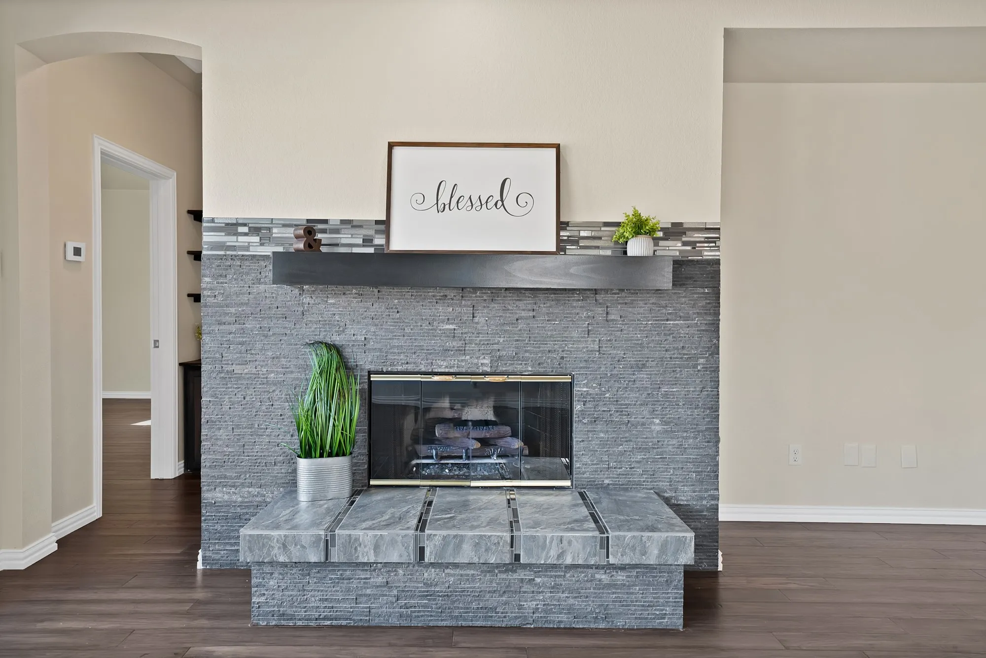 Stone veneer fireplace with an integrated hearth, a dark wood-finish mantel, and a glass-front firebox