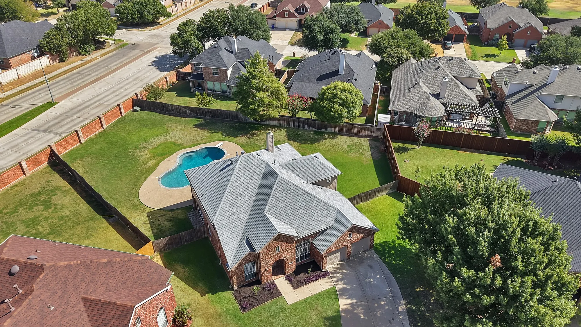 Brick exterior residence with an irregular-shaped pool, extensive rear yard, and mature landscaping