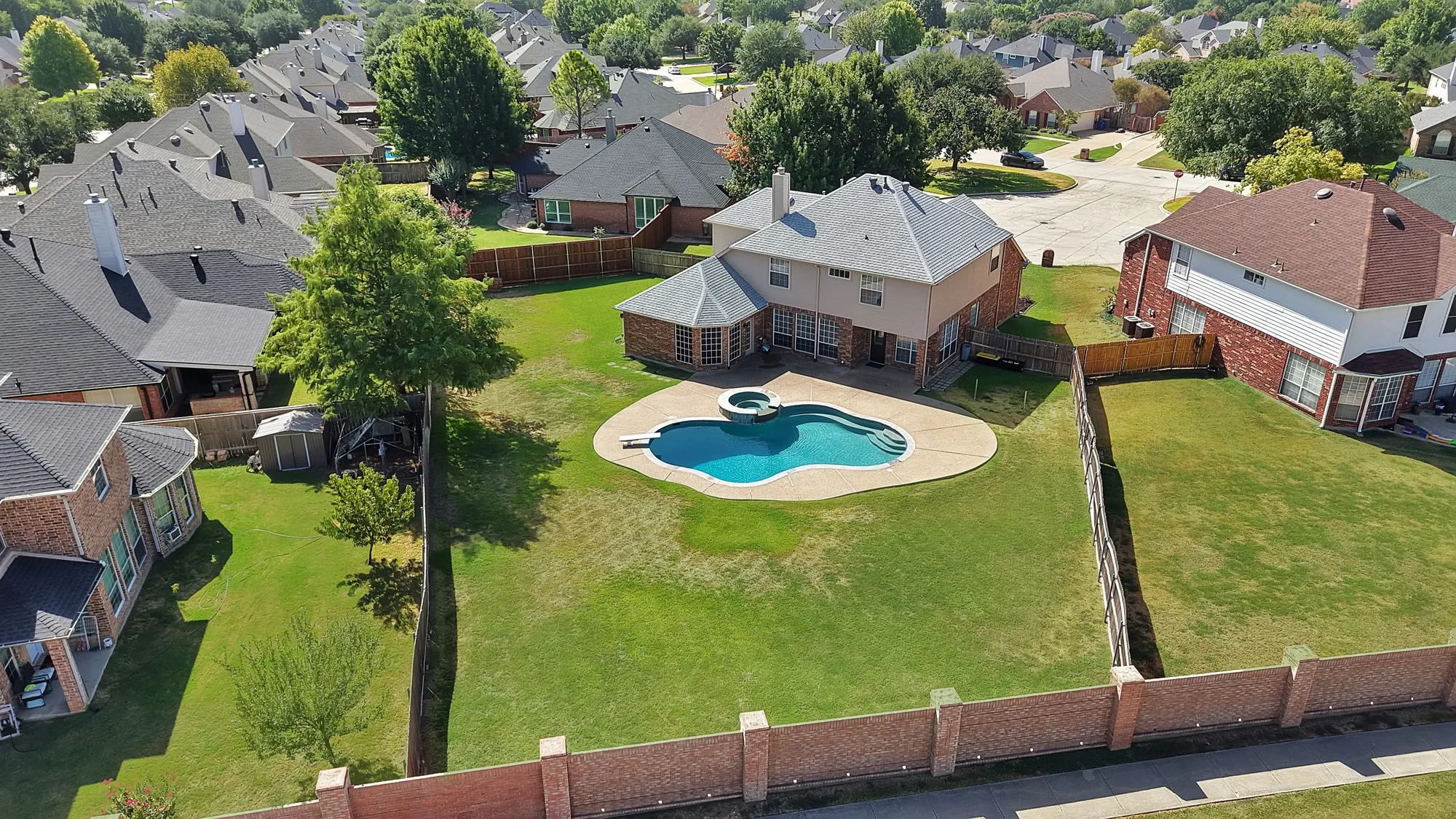 Expansive backyard featuring a large swimming pool with integrated spa, concrete decking, and mature trees