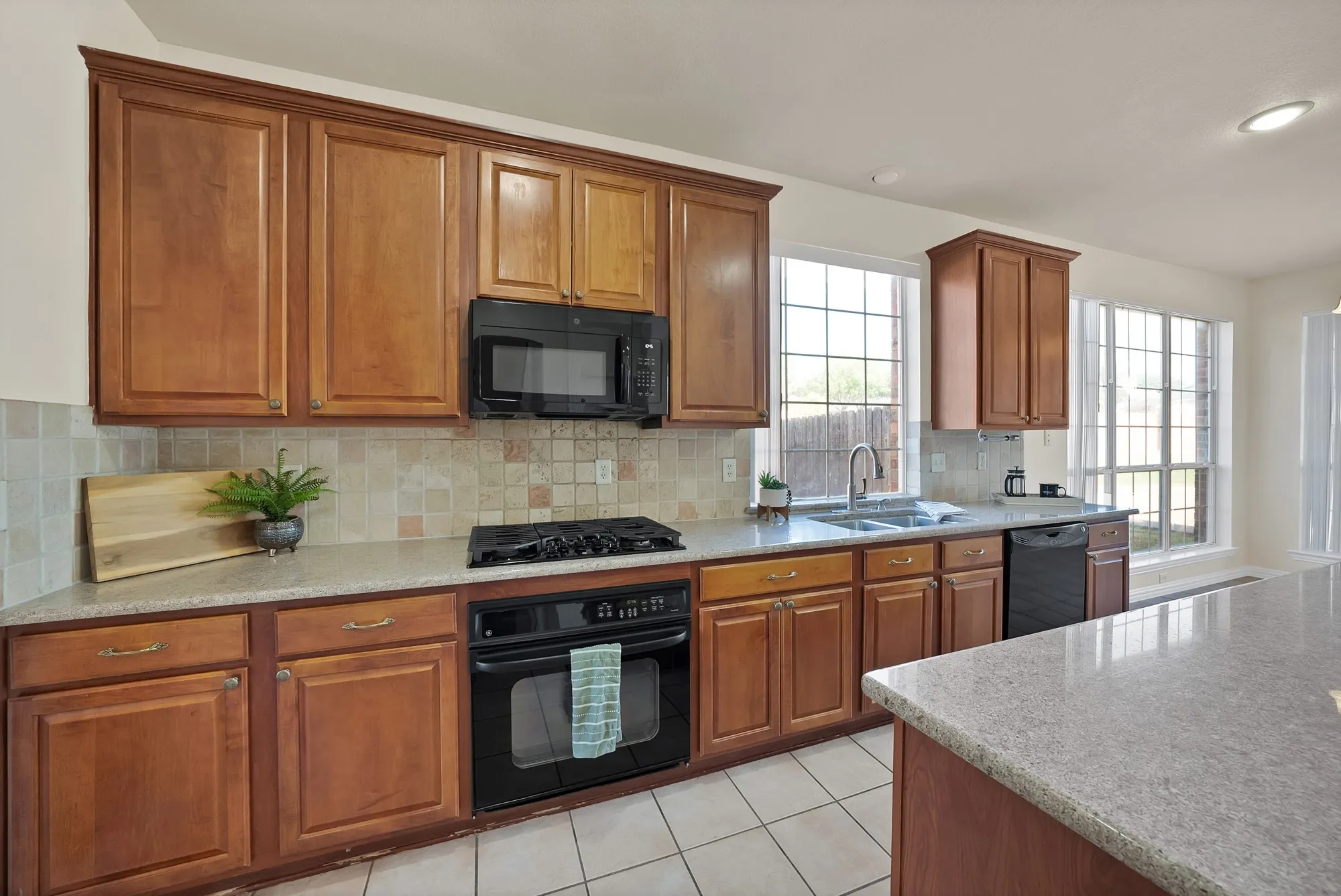 Kitchen featuring wood cabinetry, stone-finish countertops, a tile backsplash, and an integrated gas cooktop with an oven