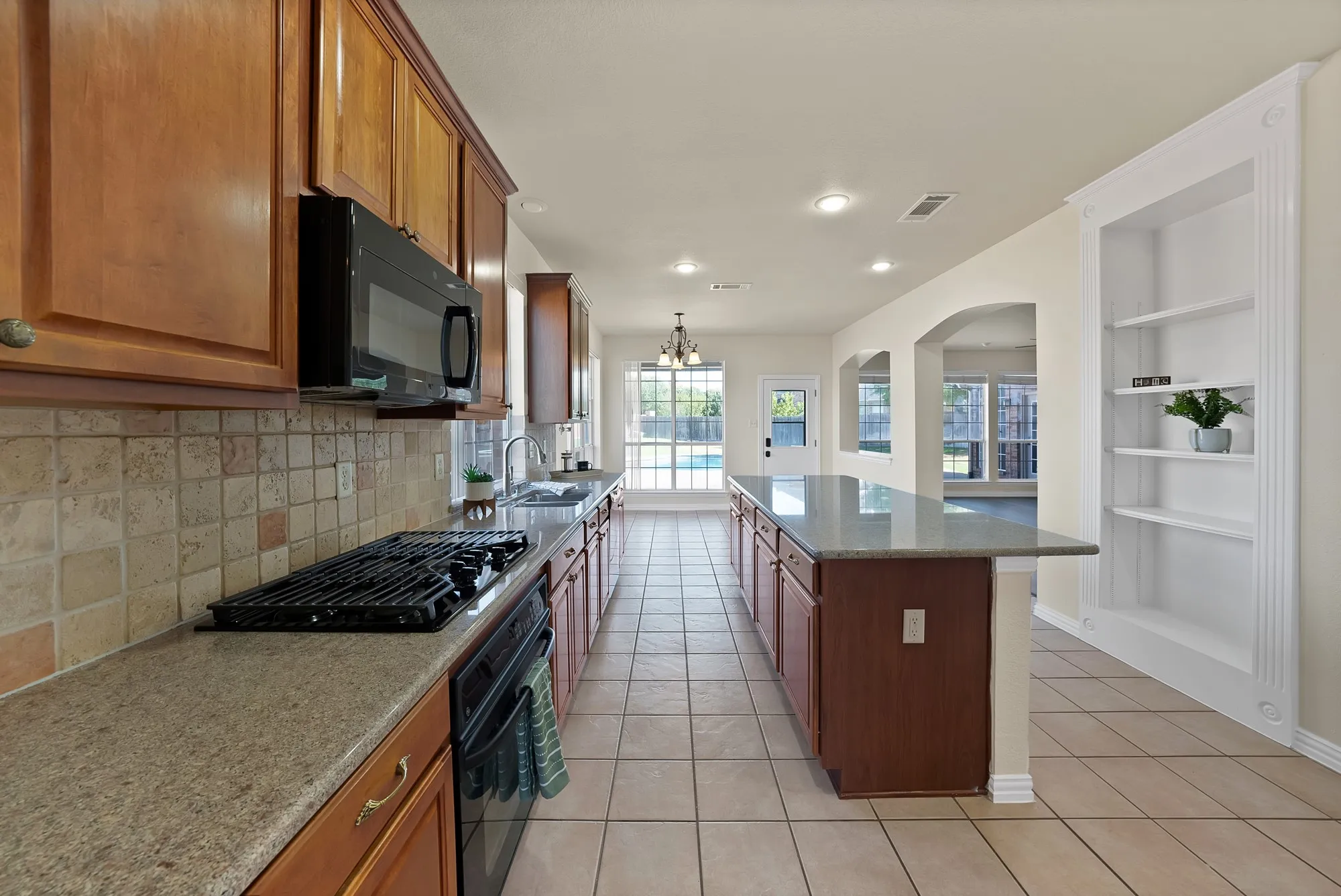 Kitchen featuring wood cabinetry, stone-finish countertops, tile backsplash, and a built-in oven with a gas cooktop