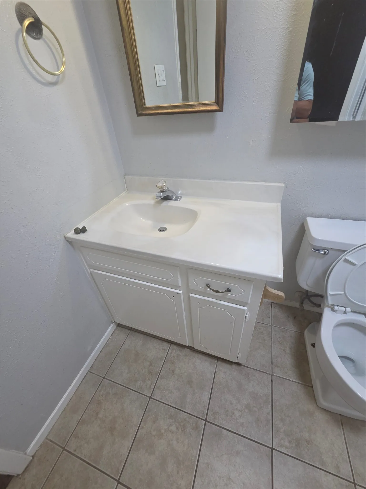 Vanity with white cabinetry, integrated sink, and a framed mirror