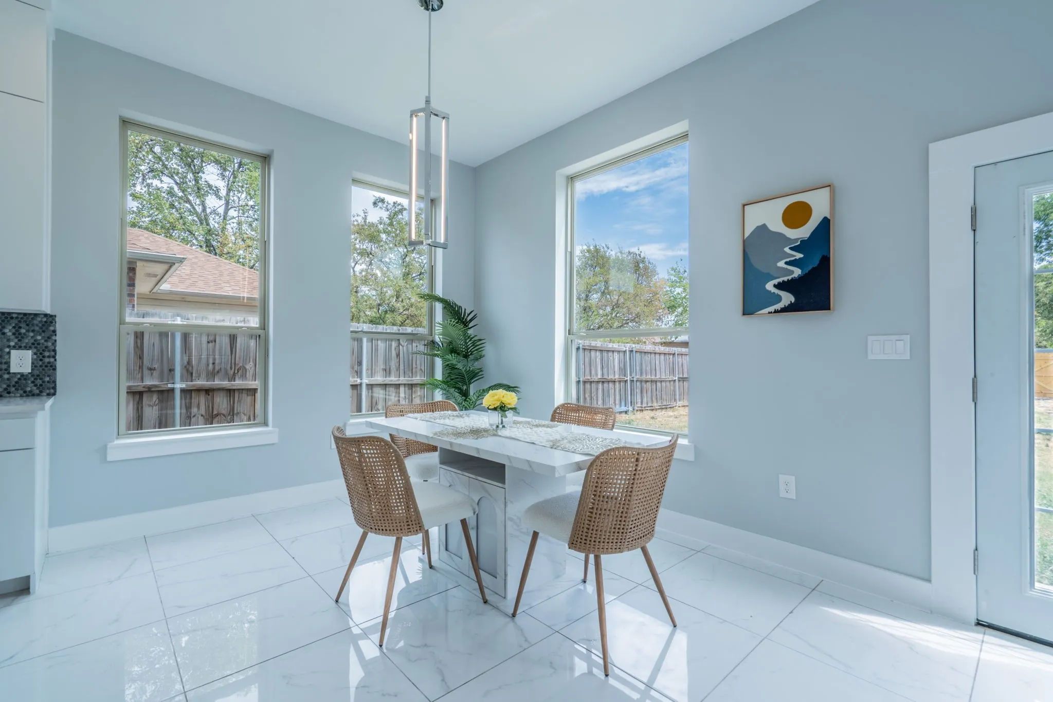White tile flooring, multiple windows, contemporary pendant lighting, light blue wall paint, and a glass-paneled door