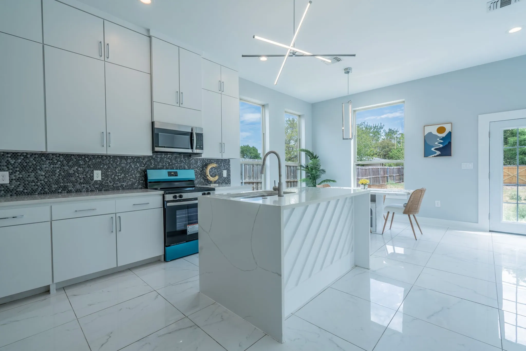 Modern kitchen featuring white cabinetry, a dark mosaic tile backsplash, stainless steel appliances, a center island with a textured facade, and large format floor tiling