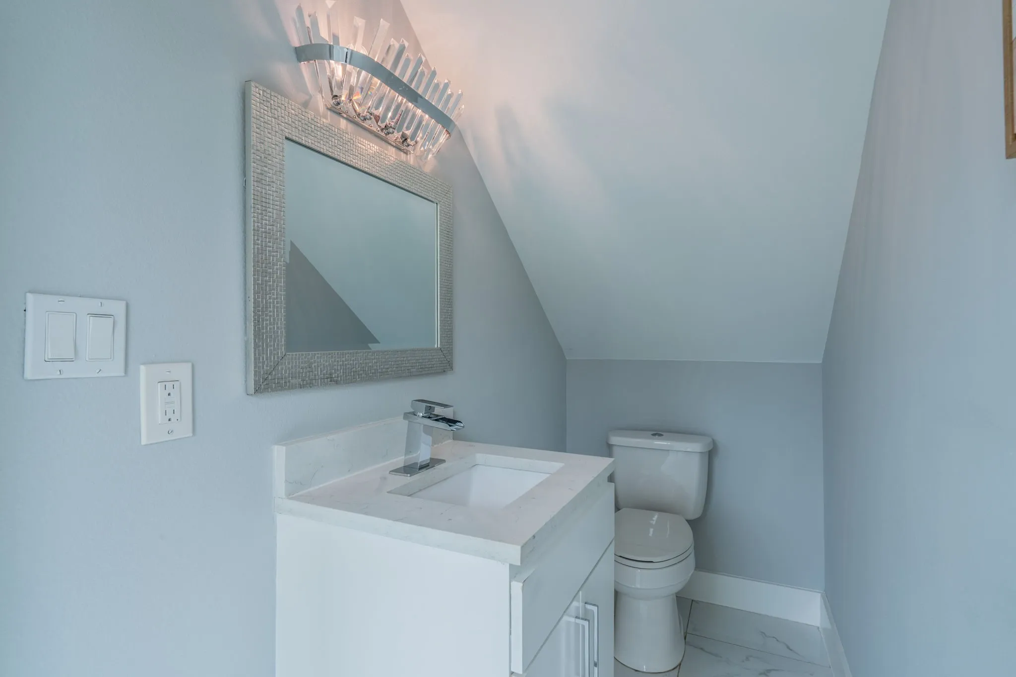 White vanity with integrated sink, chrome faucet, and quartz countertop