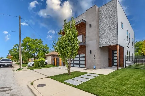 Modern exterior featuring stacked stone, stucco, wood-finish siding, and a contemporary glass panel garage door