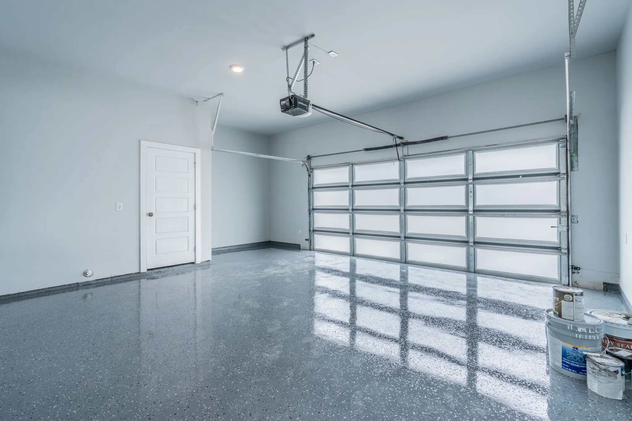 Attached garage with a light gray painted finish, an automatic overhead door, and a paneled interior door
