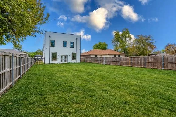 Spacious grassy yard with wood fencing and a modern white exterior