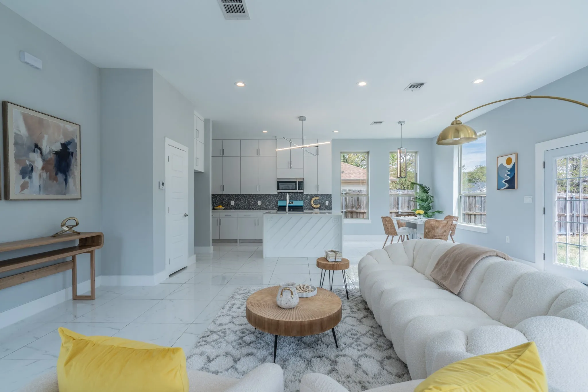 Open-concept living area featuring light-toned walls, recessed lighting, and large format tile flooring