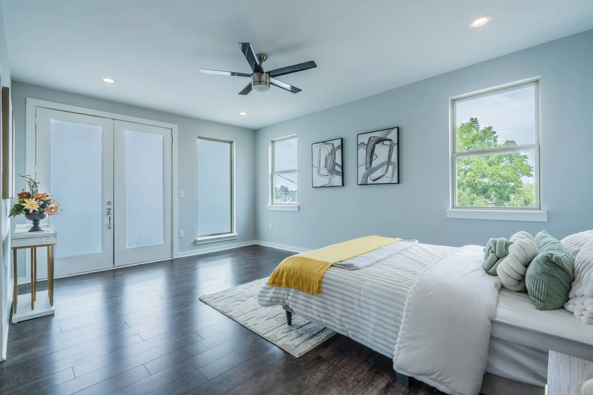 Wood-finish flooring, recessed lighting, ceiling fan, multiple windows, and double doors with frosted glass panels