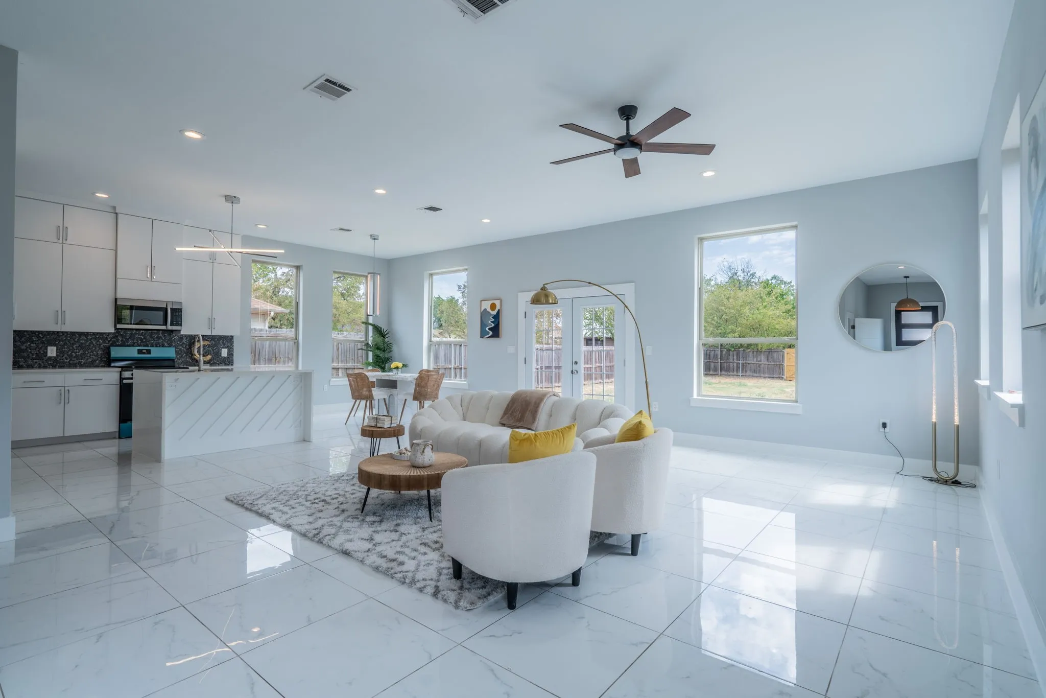 Bright living area featuring large format tile flooring, a ceiling fan, recessed lighting, and multiple windows