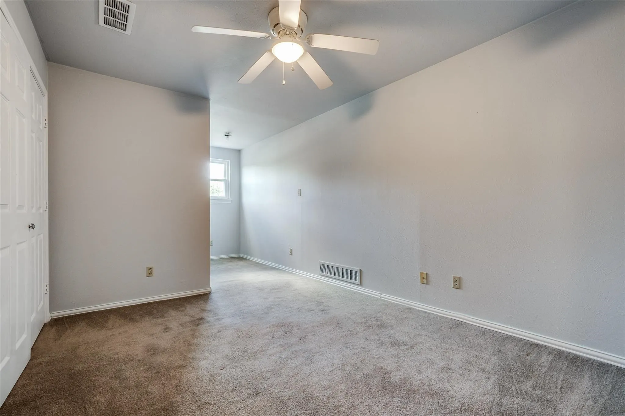Carpeted room with a ceiling fan, white trim, and a window
