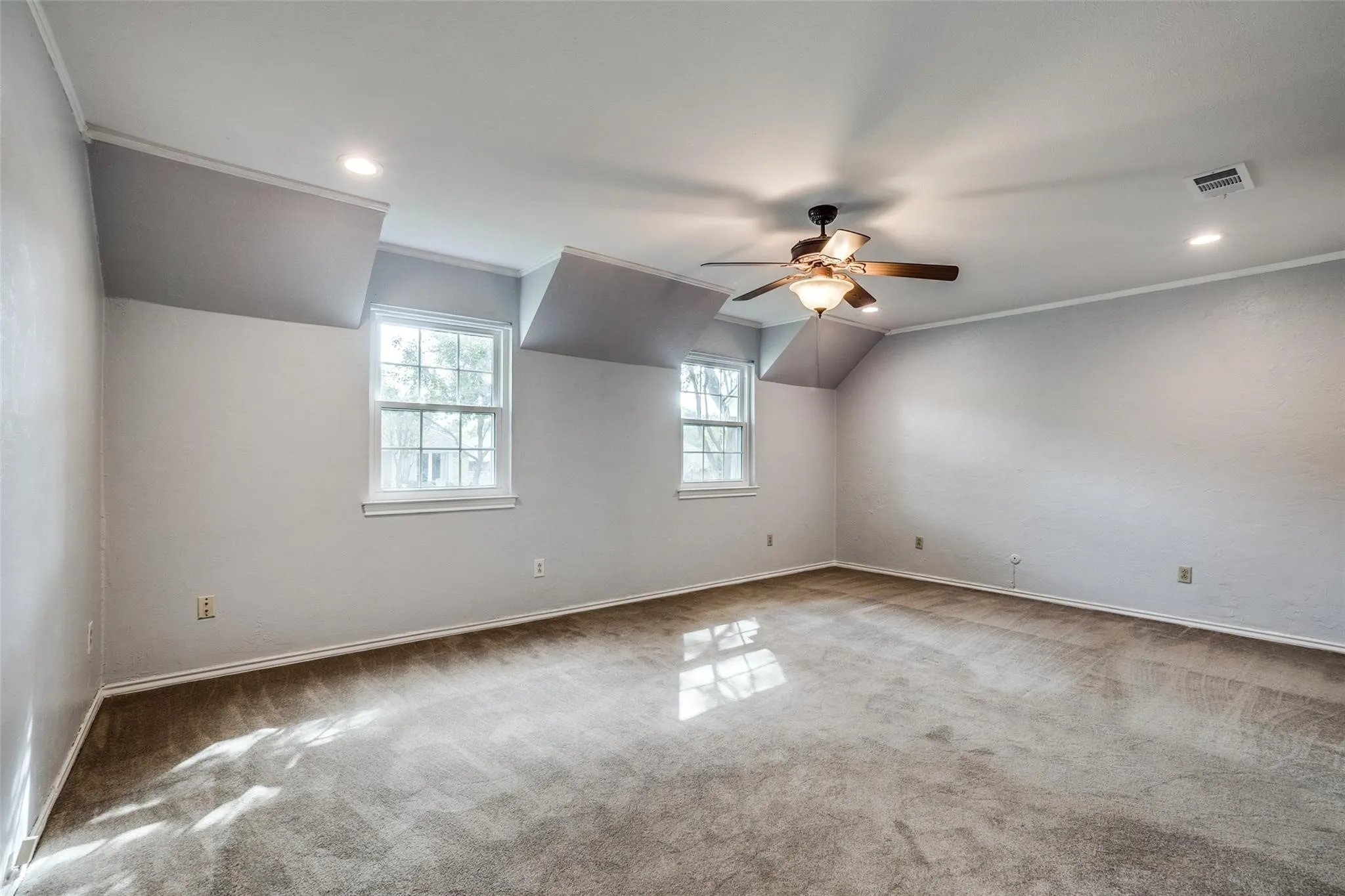 Expansive room featuring two windows, recessed lighting, crown molding, and a ceiling fan with integrated lighting